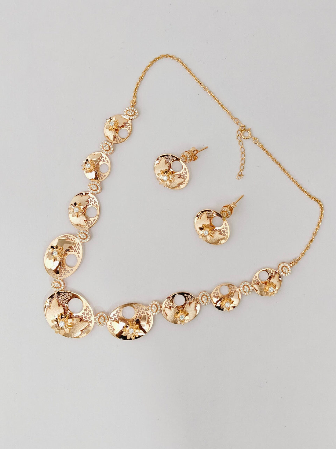 Gold necklace and earrings set on a gray background