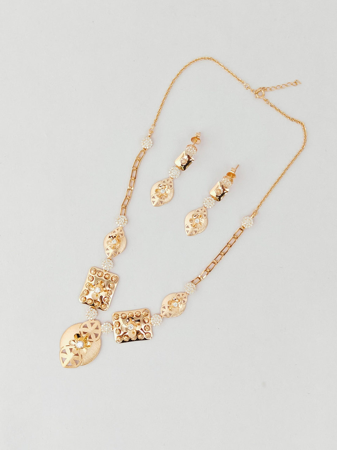 Gold necklace and earrings set on a light gray background