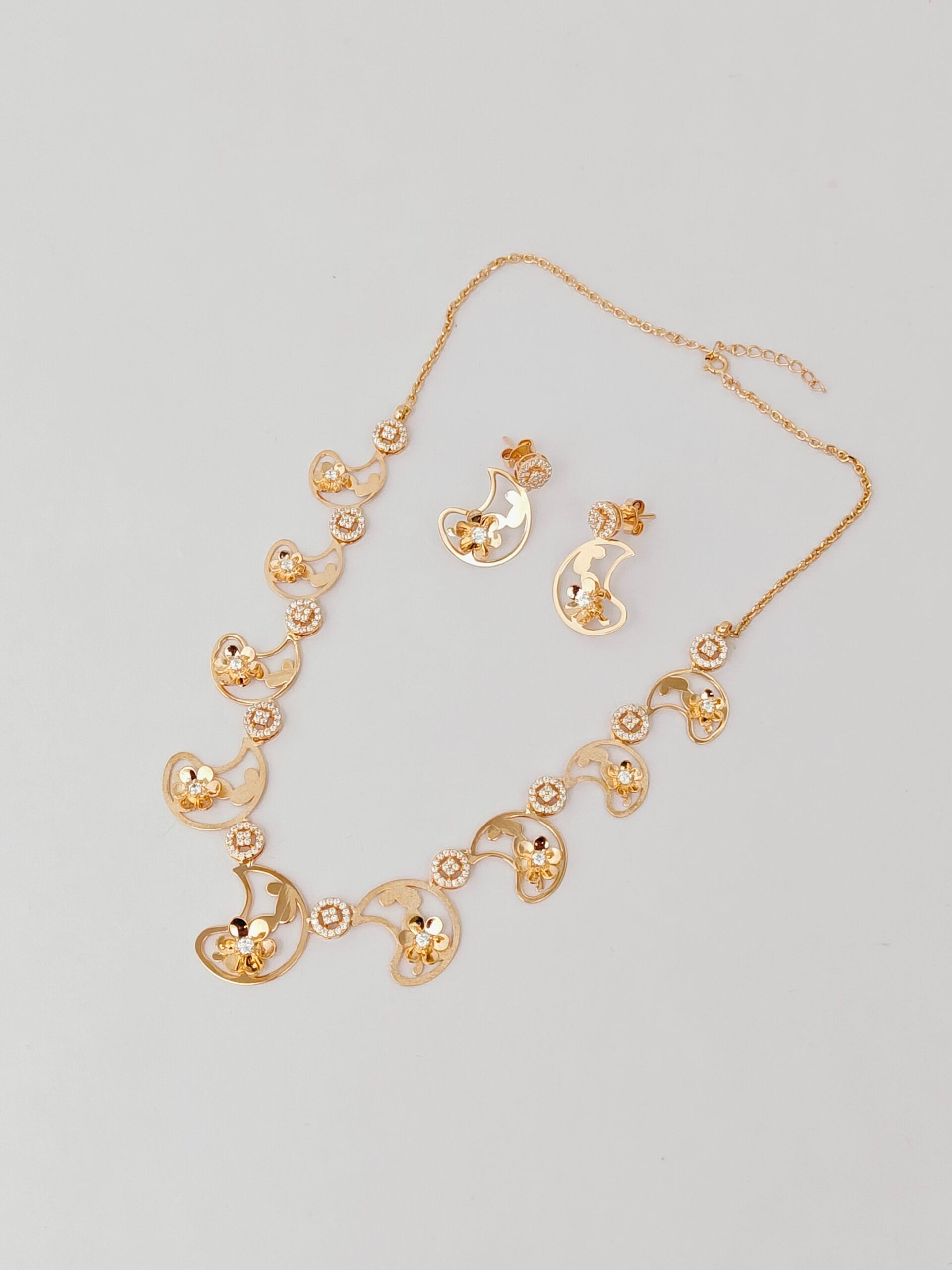 Gold necklace and earrings set on a light gray background