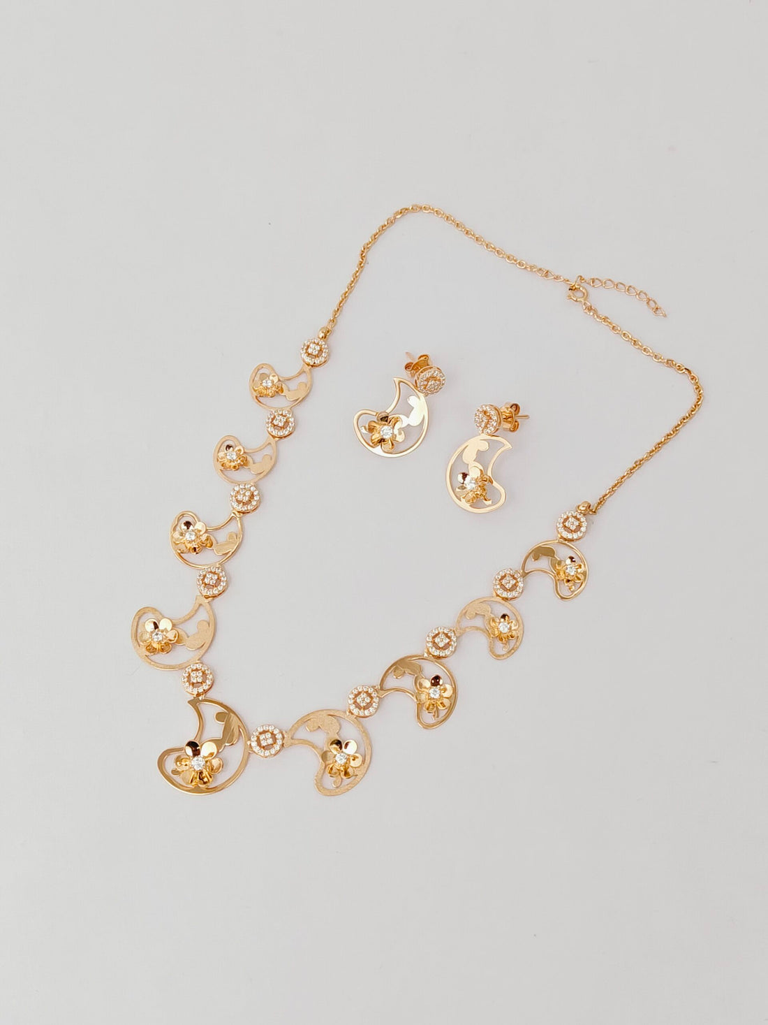 Gold necklace and earrings set on a light gray background