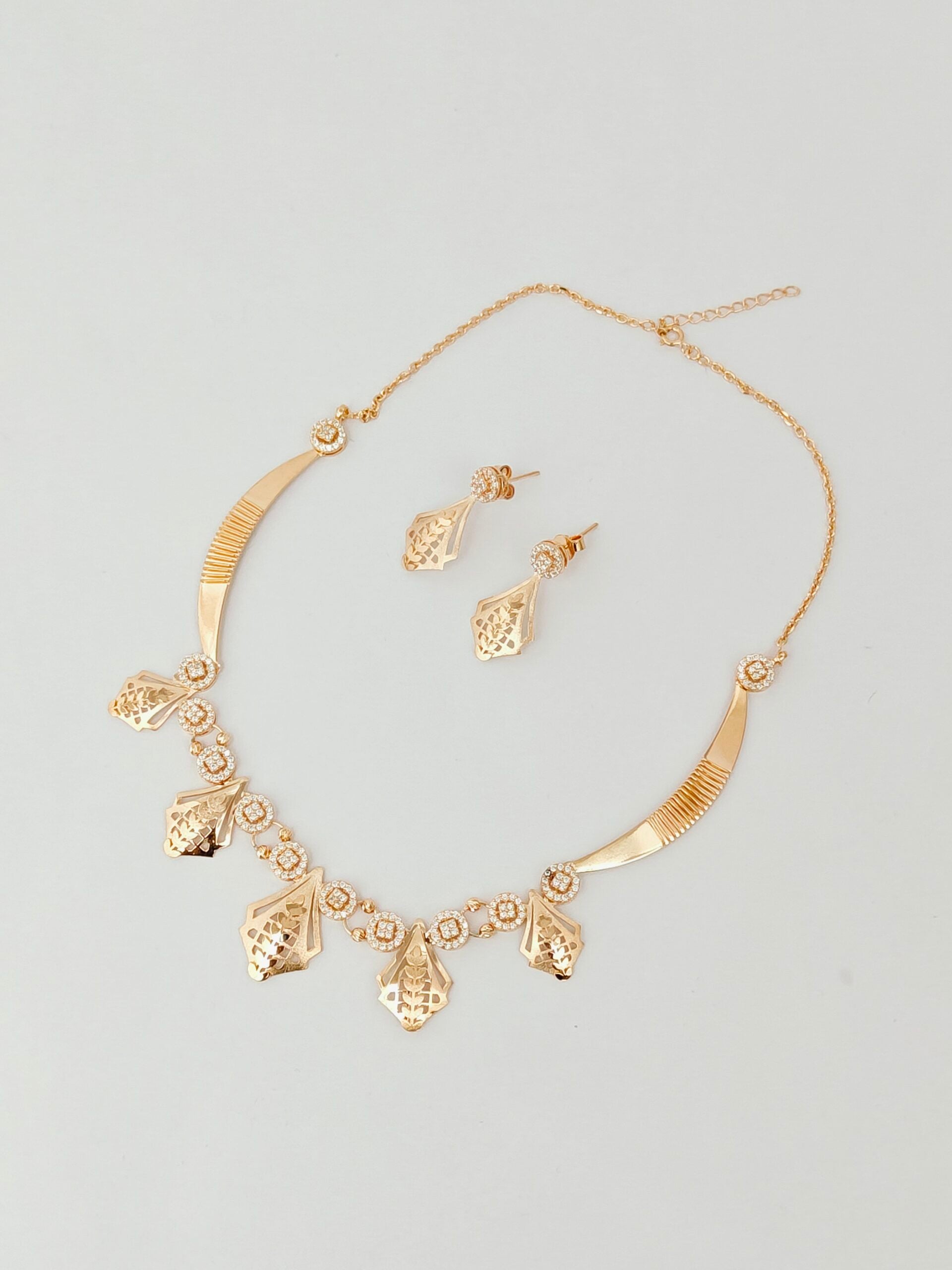 Gold necklace and earrings set on a light gray background