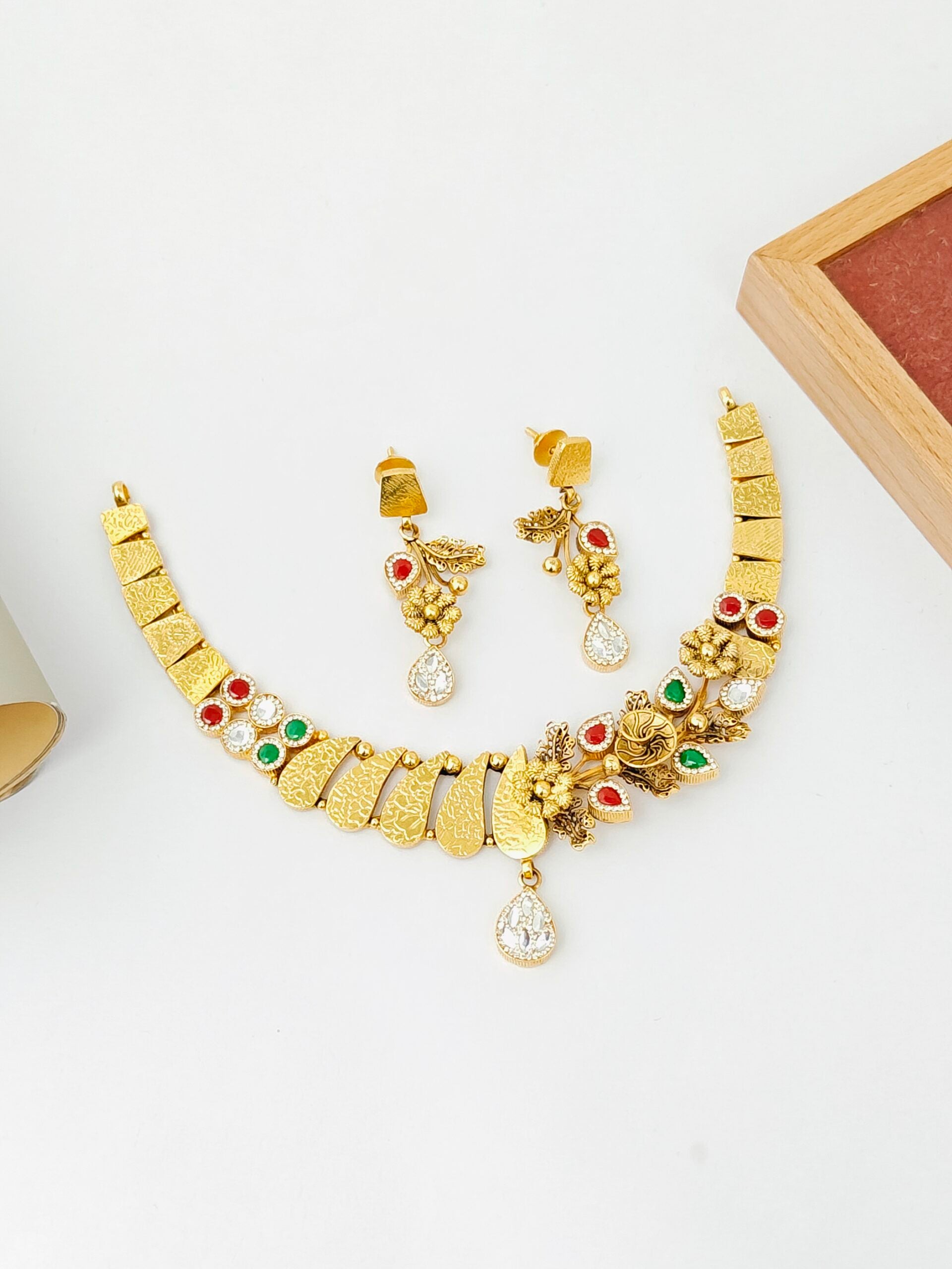 Gold necklace and earrings set on a white surface