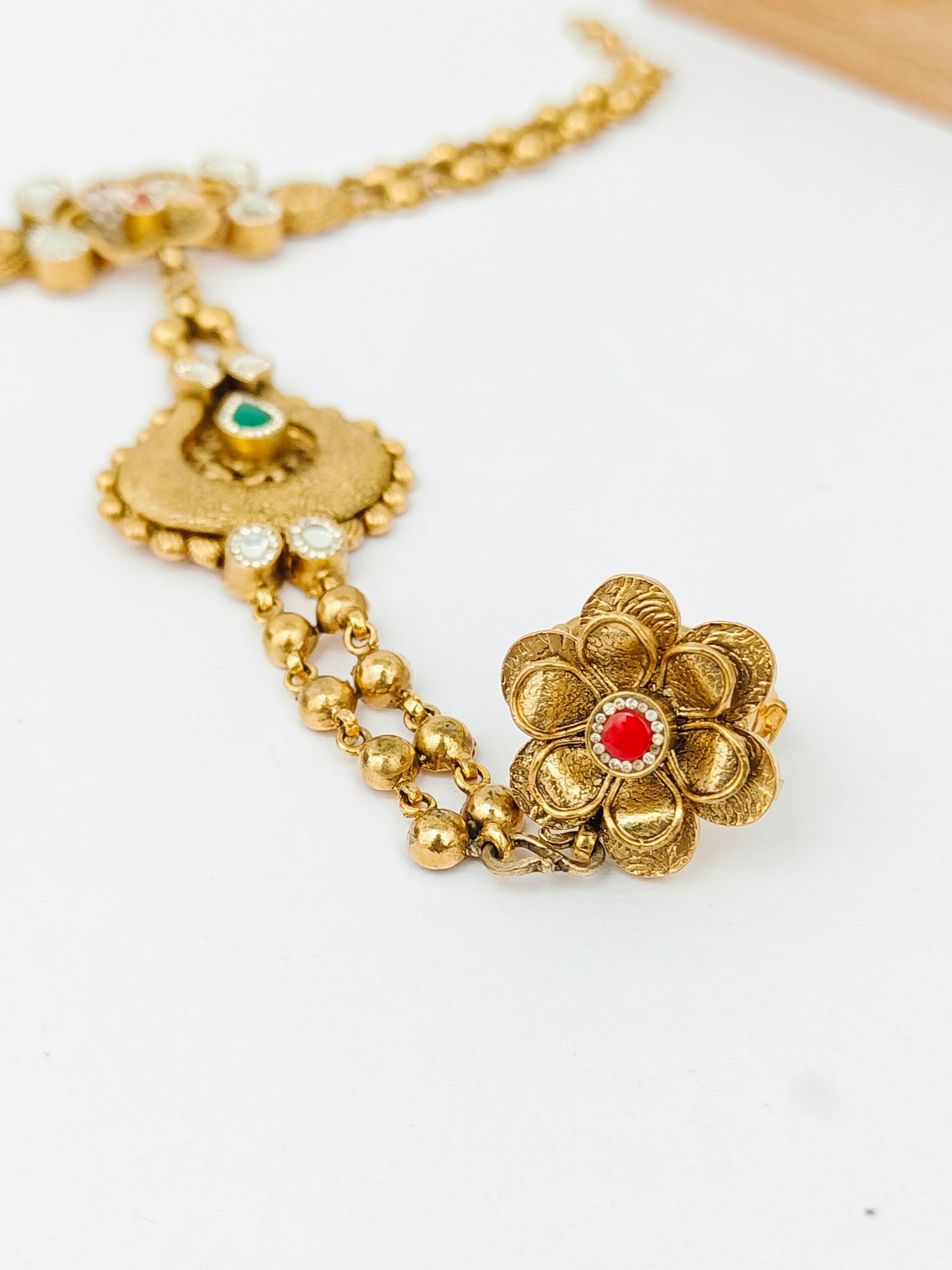 Gold necklace with floral design on a white background