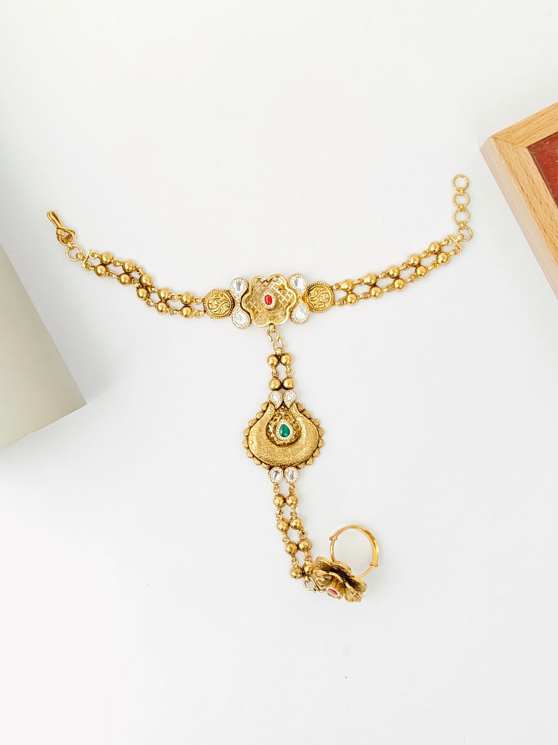 Gold necklace with intricate design on a white surface