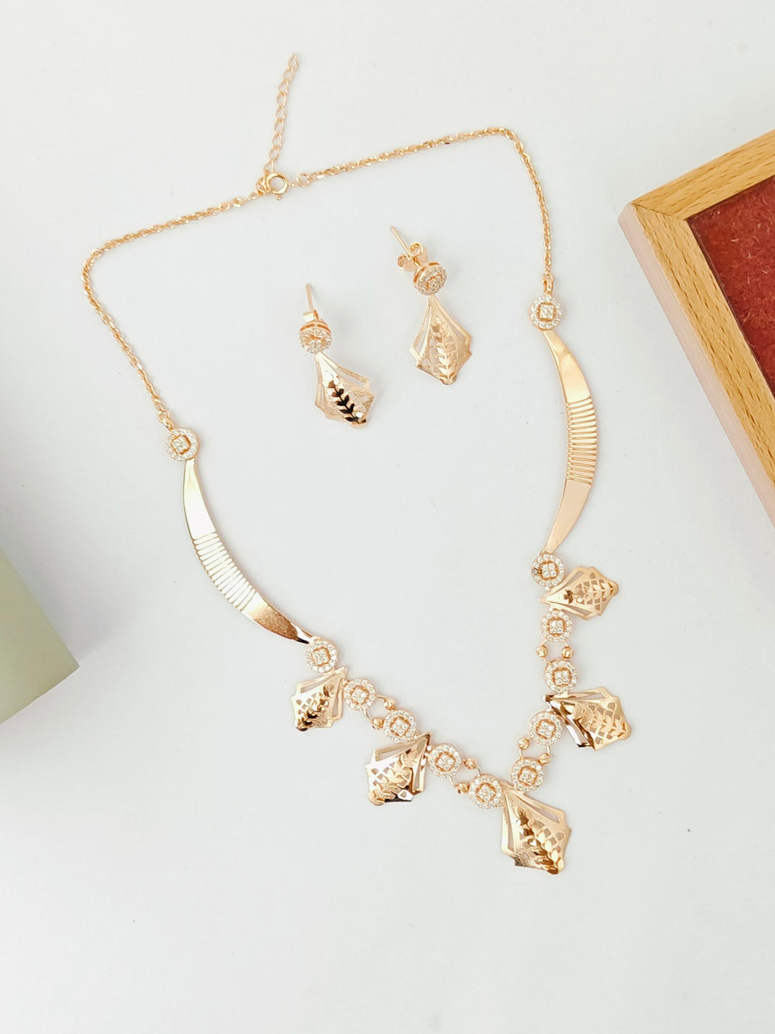 Gold necklace and earrings set on a light background