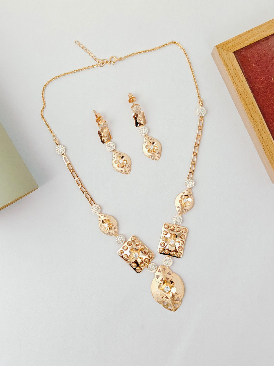 Gold necklace and earrings set on a light gray surface