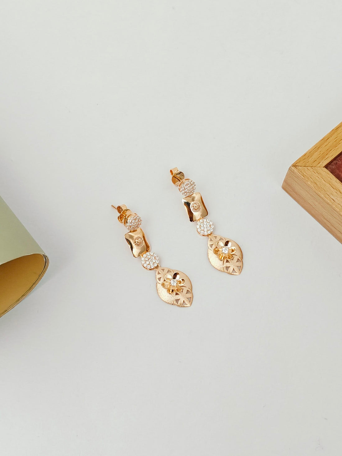 Gold earrings with clear stones on a light gray surface