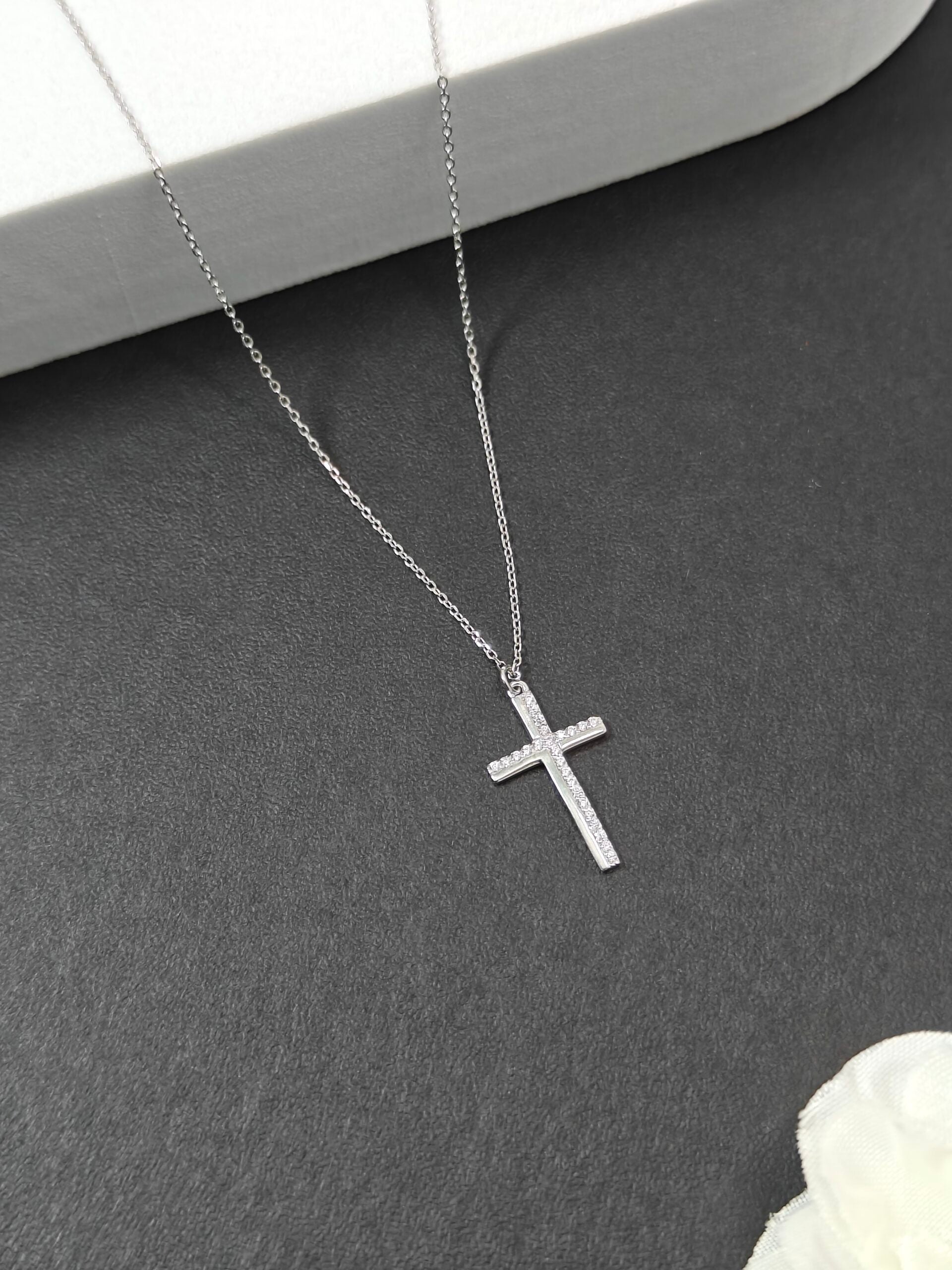 Silver cross necklace on a dark surface