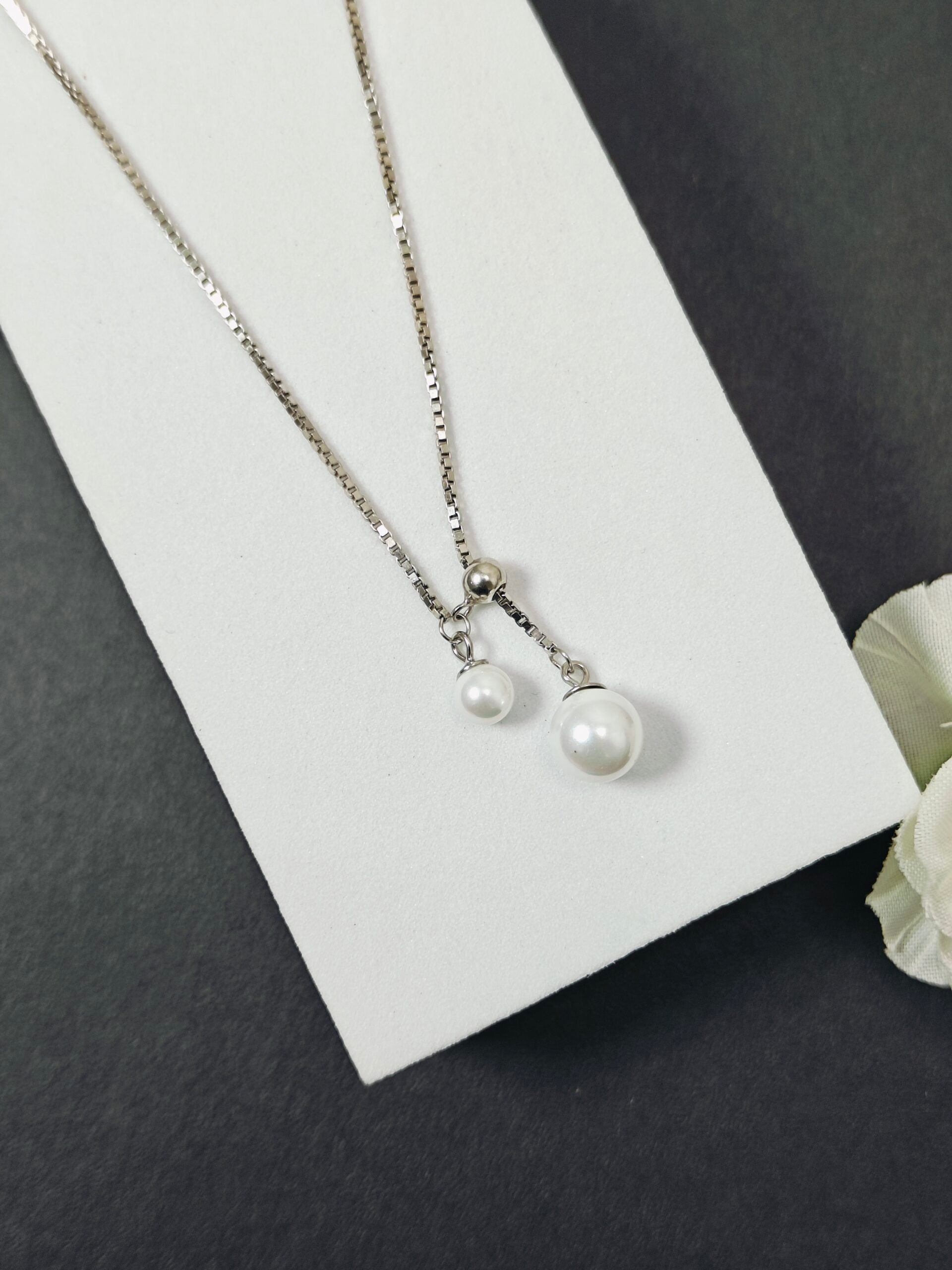 Pearl necklace on a white card with a gray background