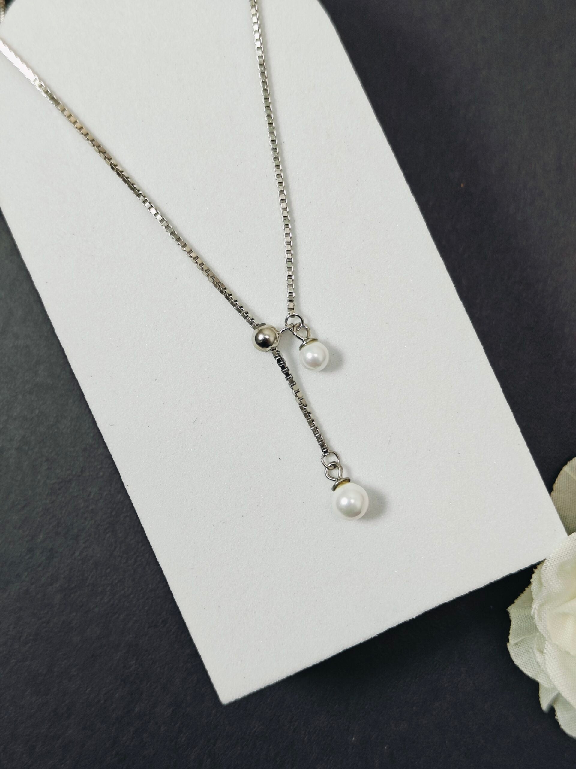 Necklace with pearls on a white card against a dark background