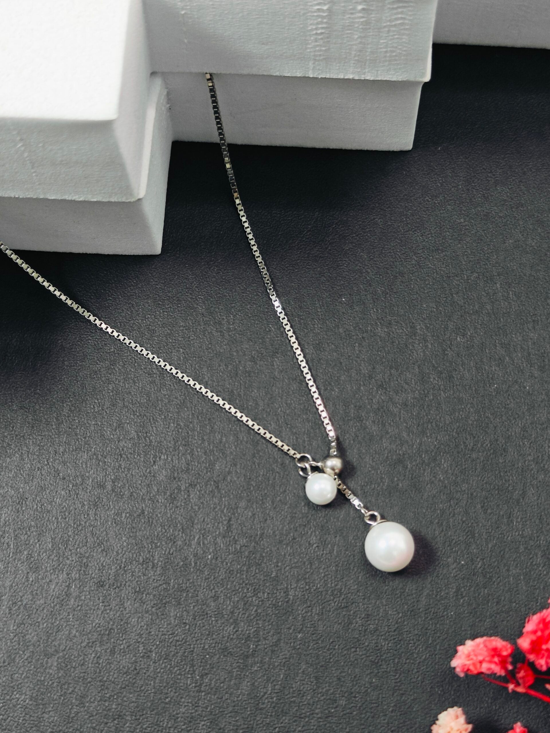 Pearl necklace on a dark surface with a white box in the background