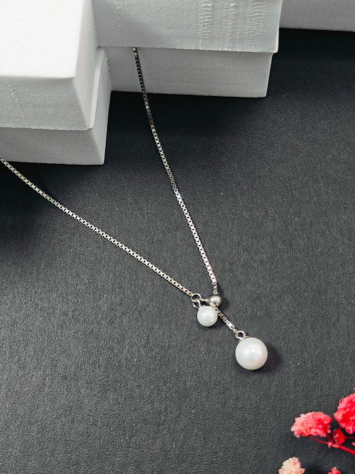 Pearl necklace on a dark surface with a white box in the background
