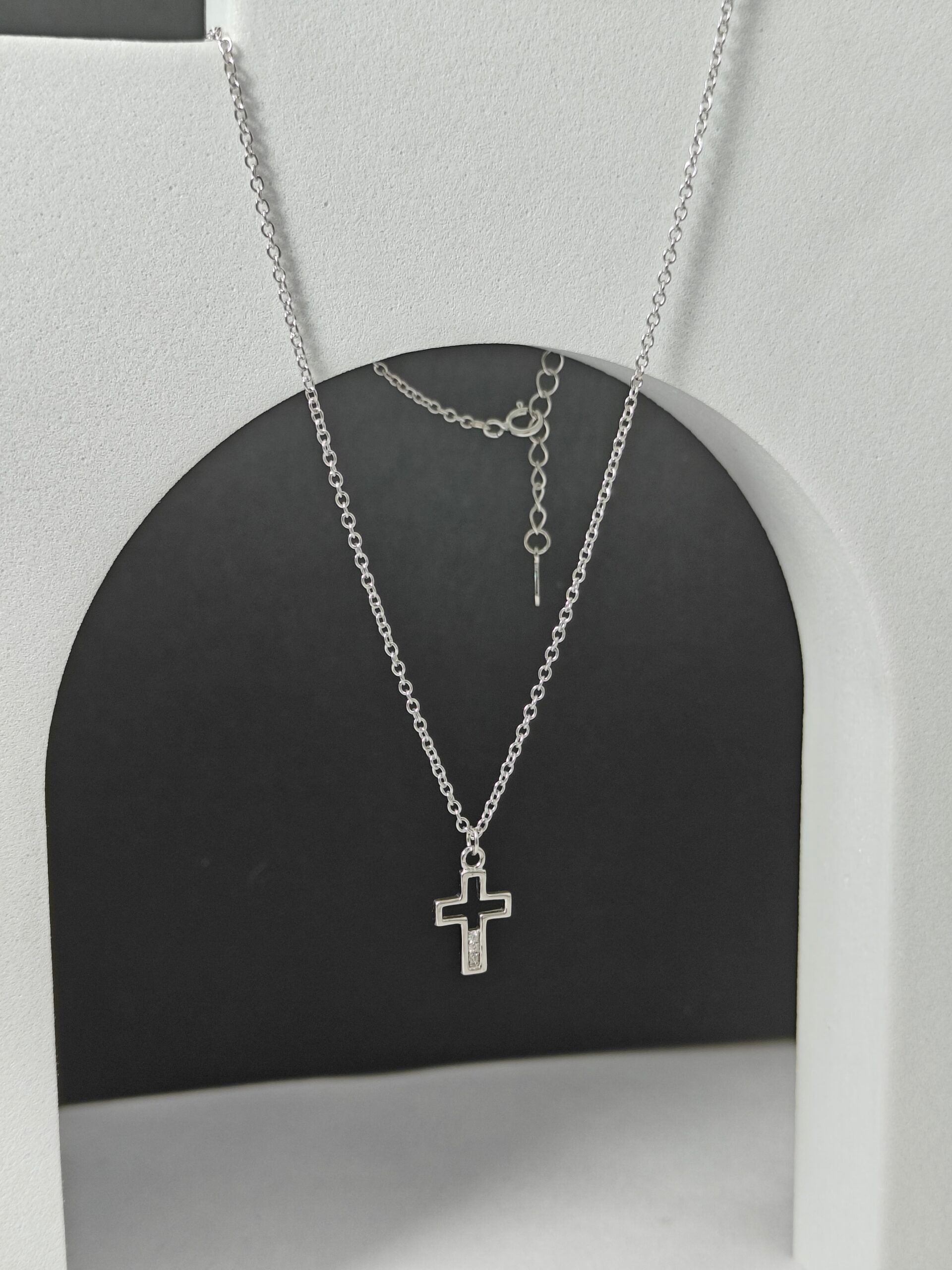 Silver necklace with a cross pendant on a black and gray background