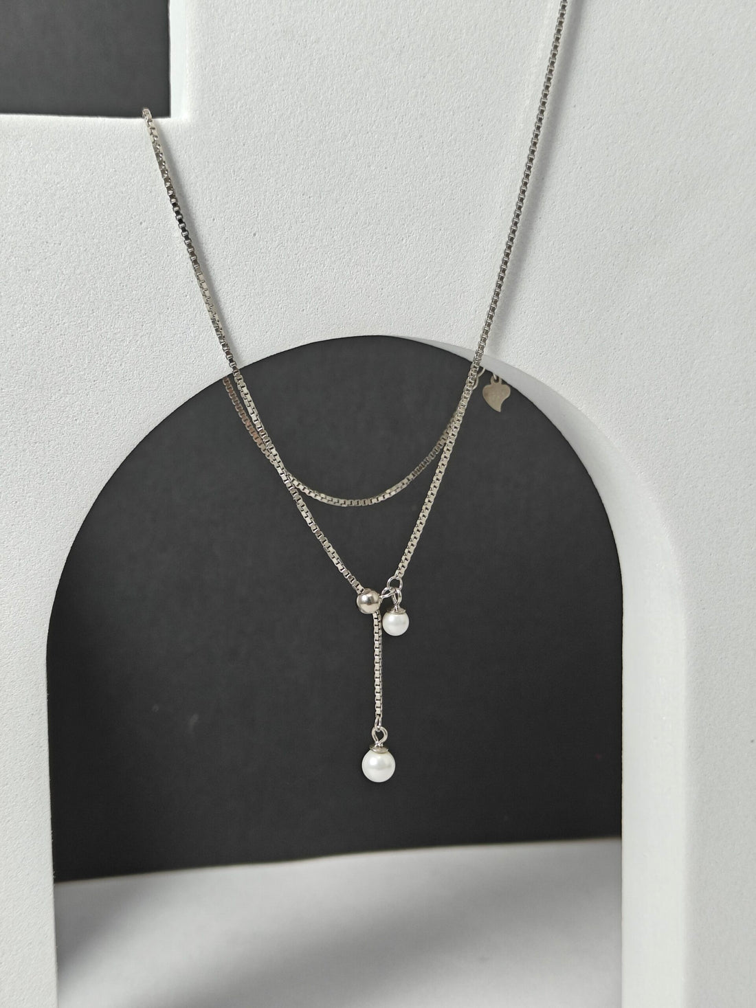 Silver necklace with pendant on a black and gray background