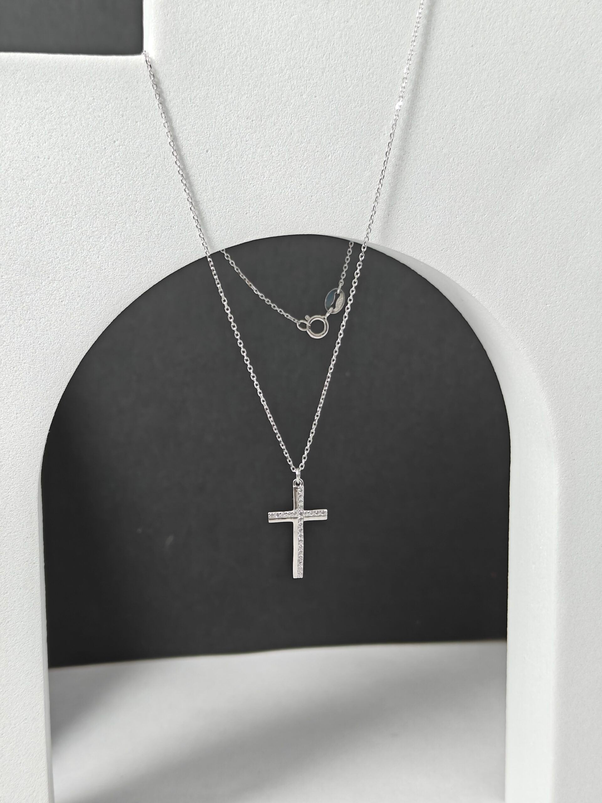 Silver cross necklace on a black and white background