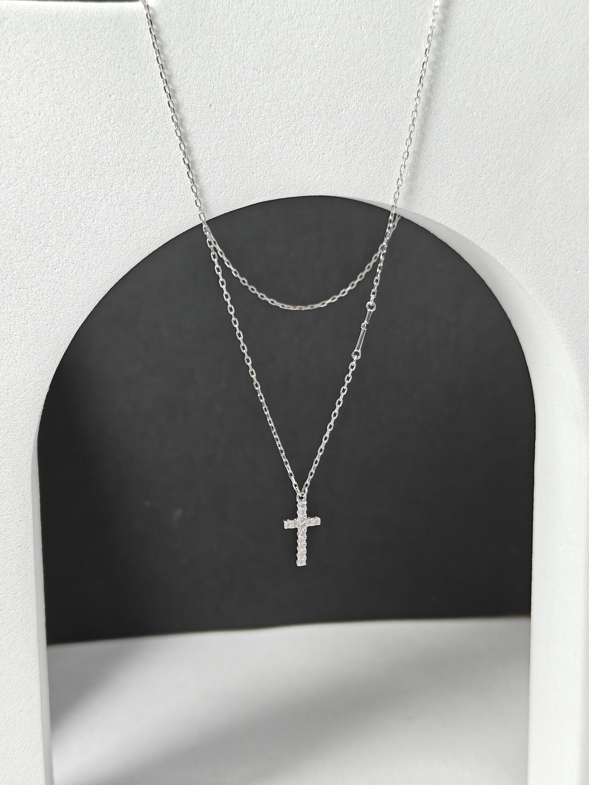 Silver cross necklace on a black and white background