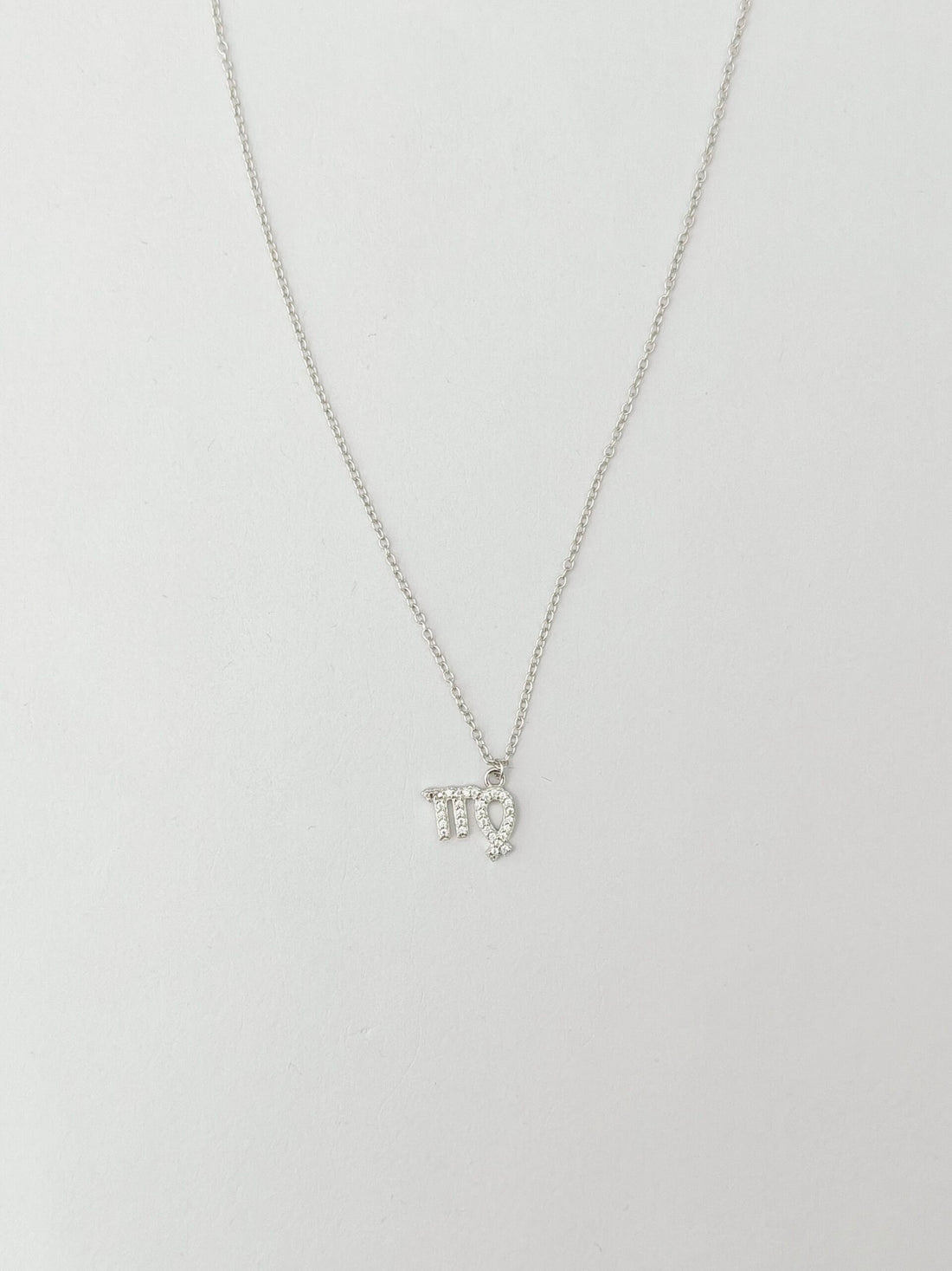 Silver necklace with a small pendant on a light gray background
