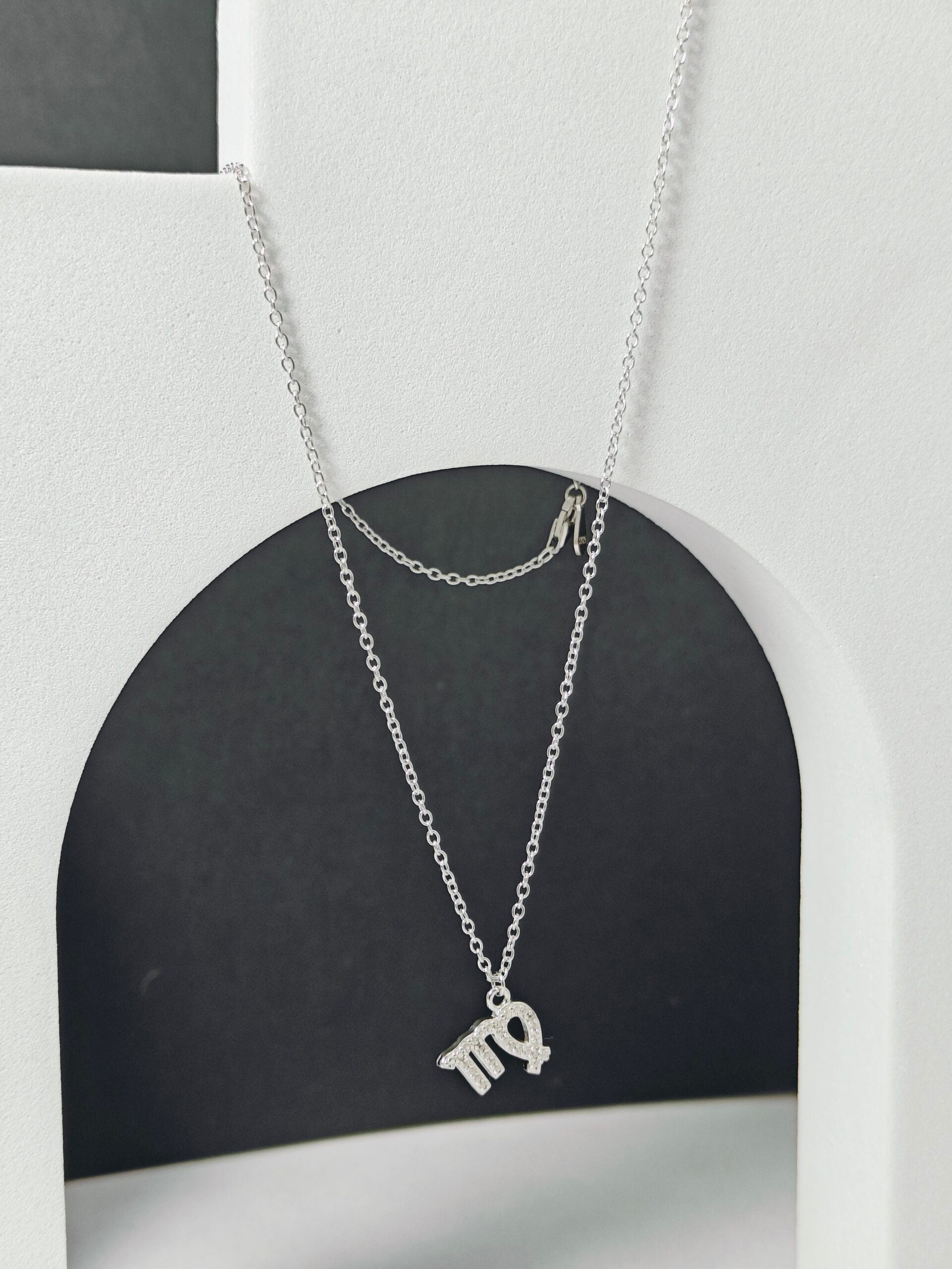 Silver necklace with a pendant on a black and white background