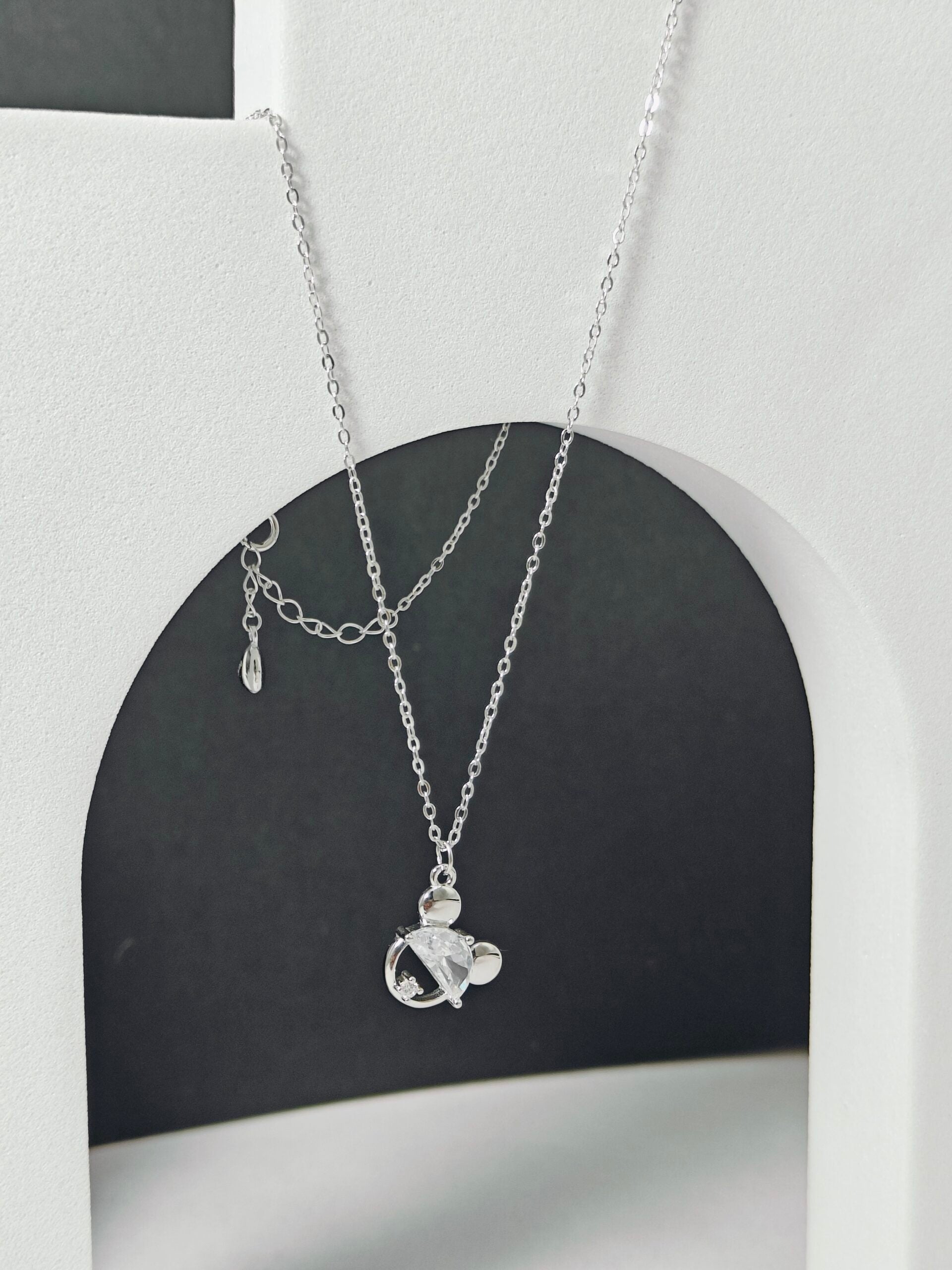 Silver necklace with a pendant on a black and white background