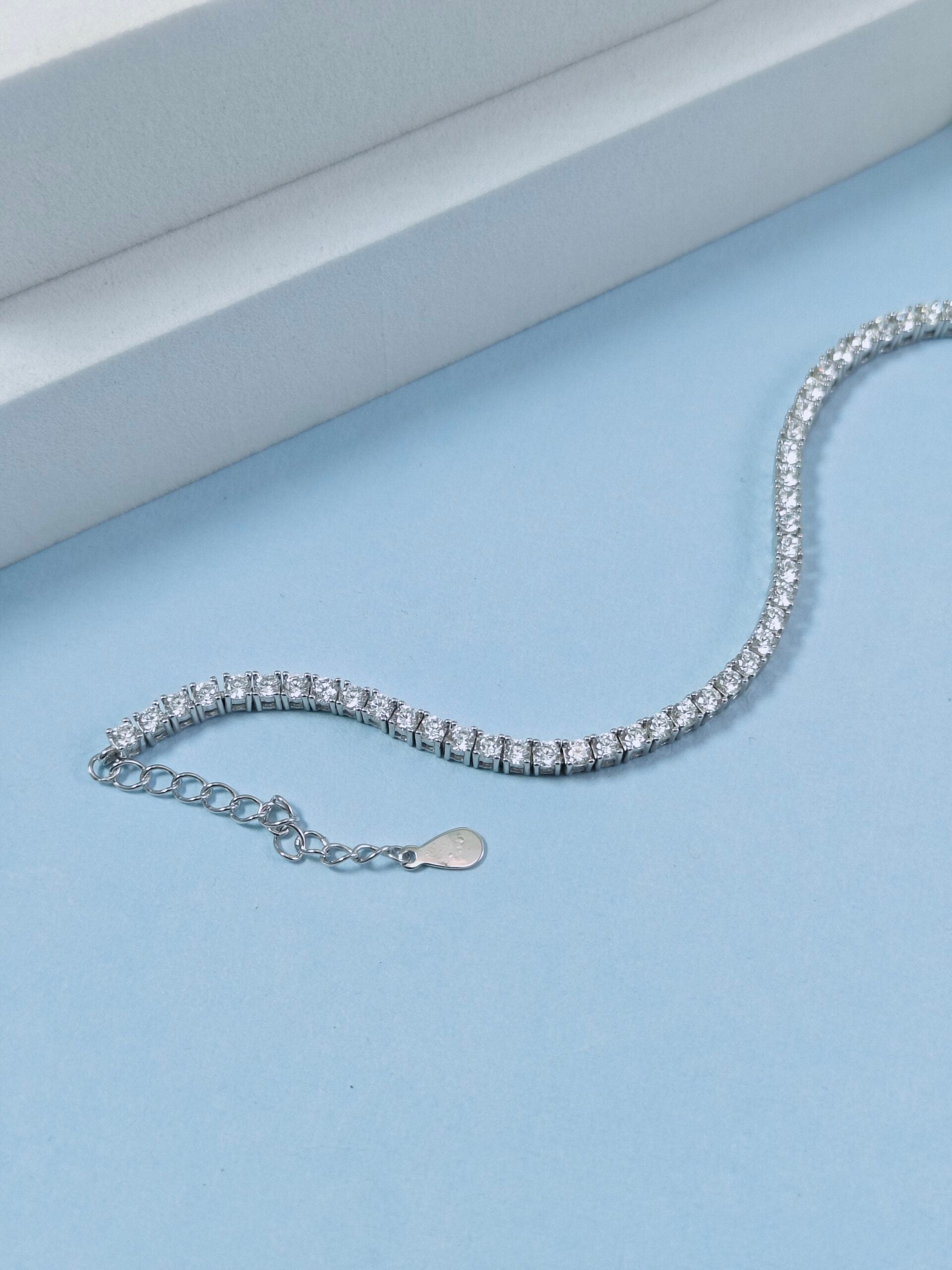 Silver bracelet on a light blue surface