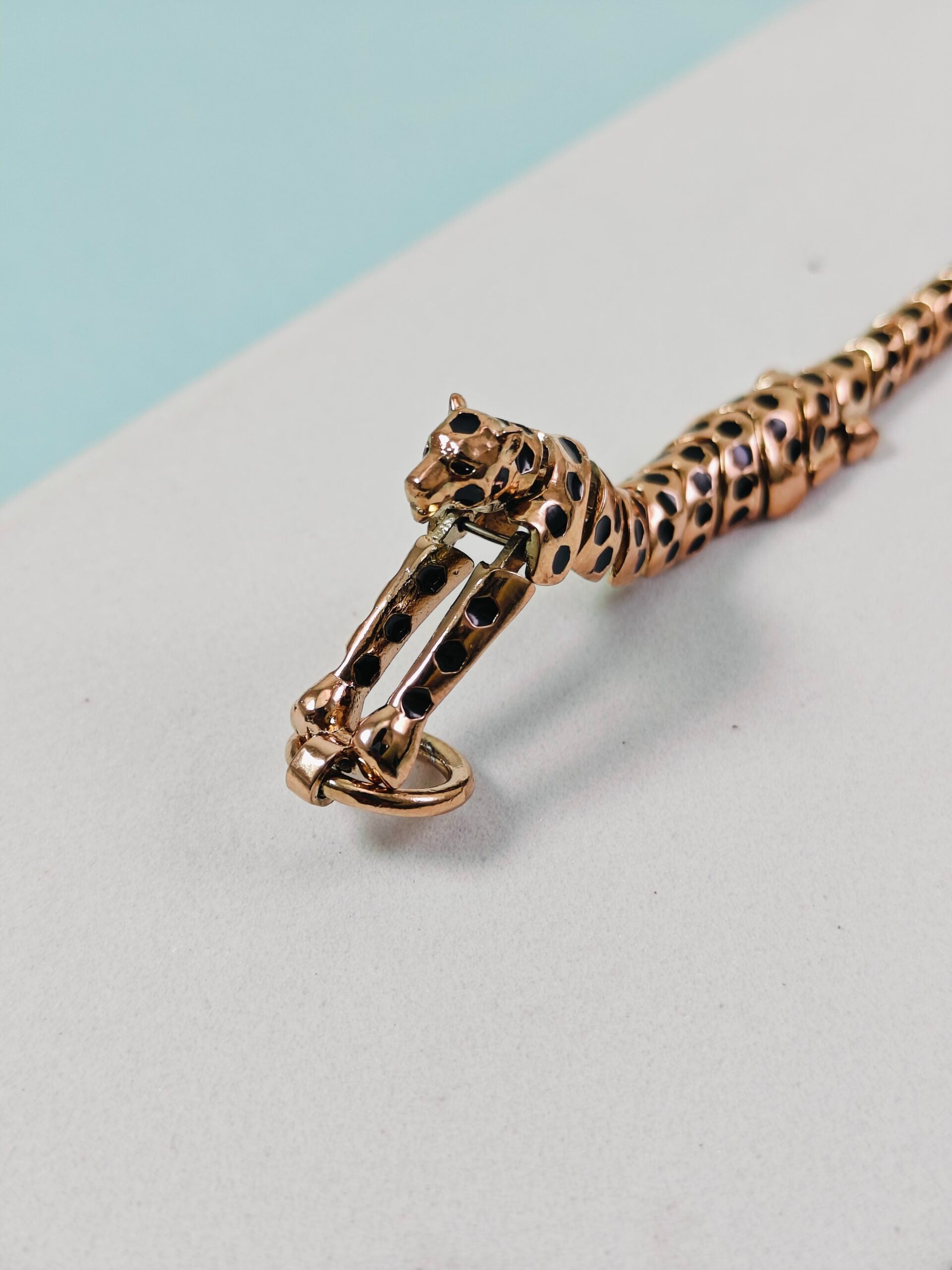 Gold bracelet with a panther design on a light gray surface
