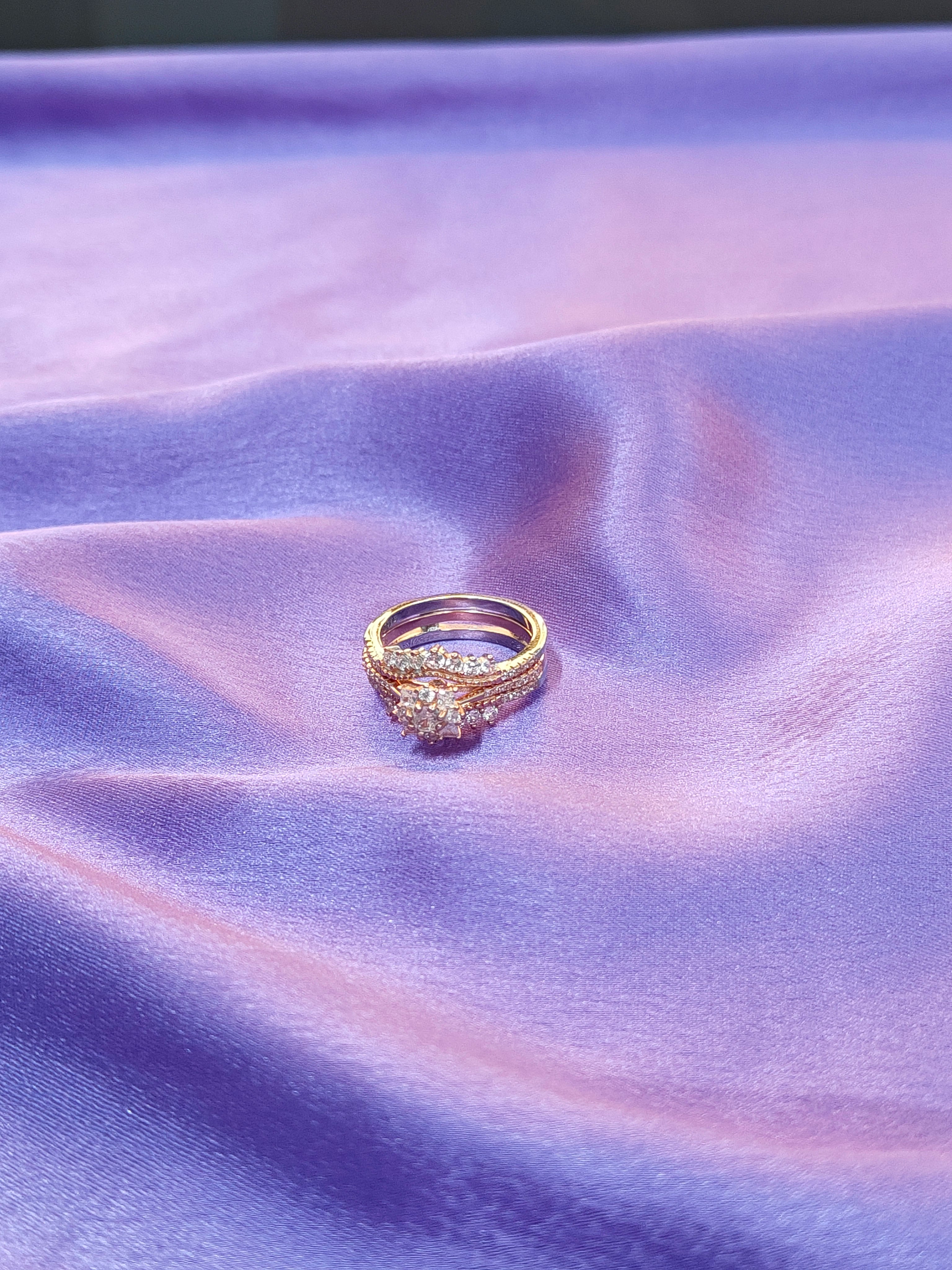 Gold ring with diamonds on a purple fabric background