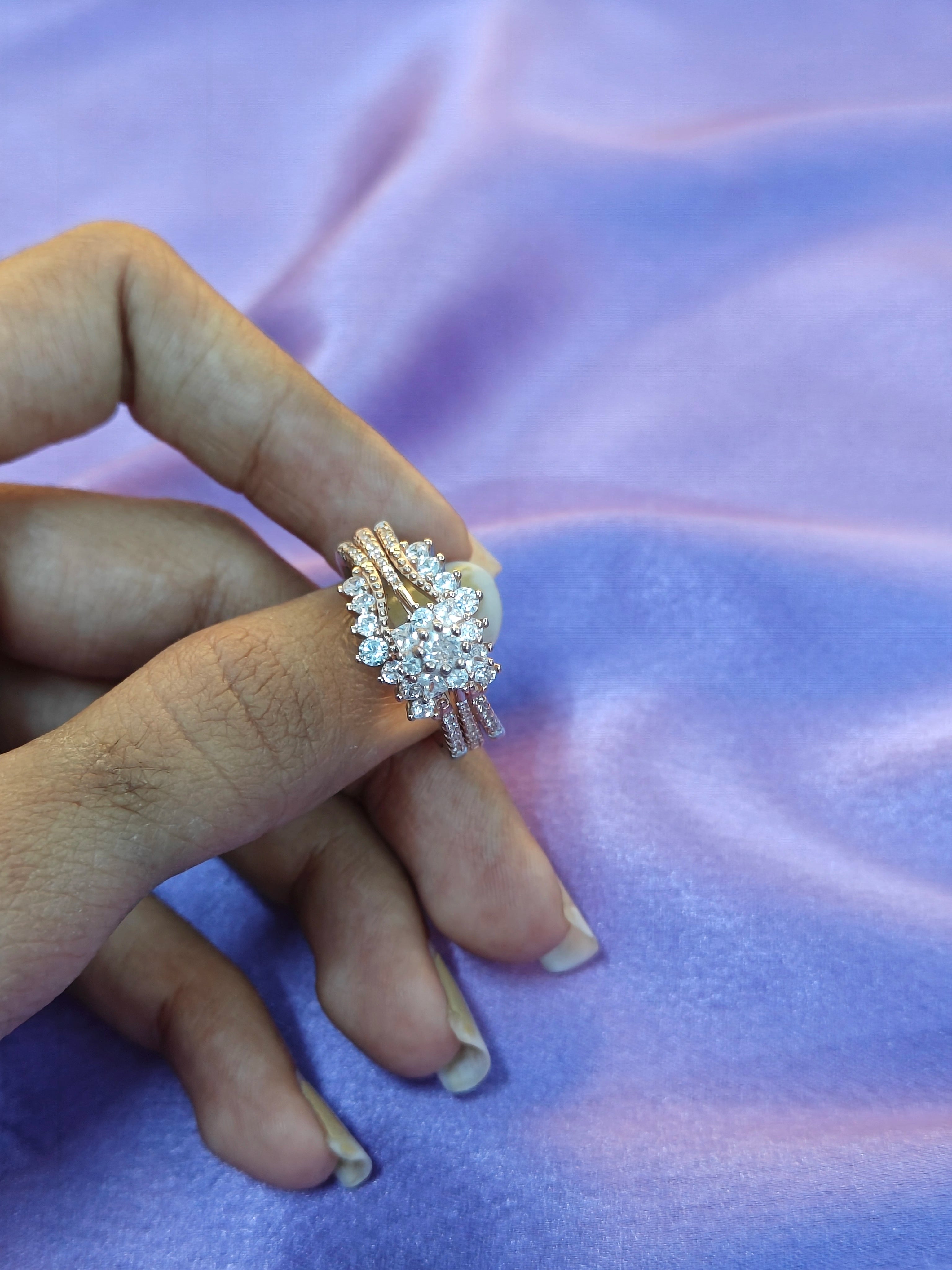 Hand wearing a decorative ring on a purple fabric background