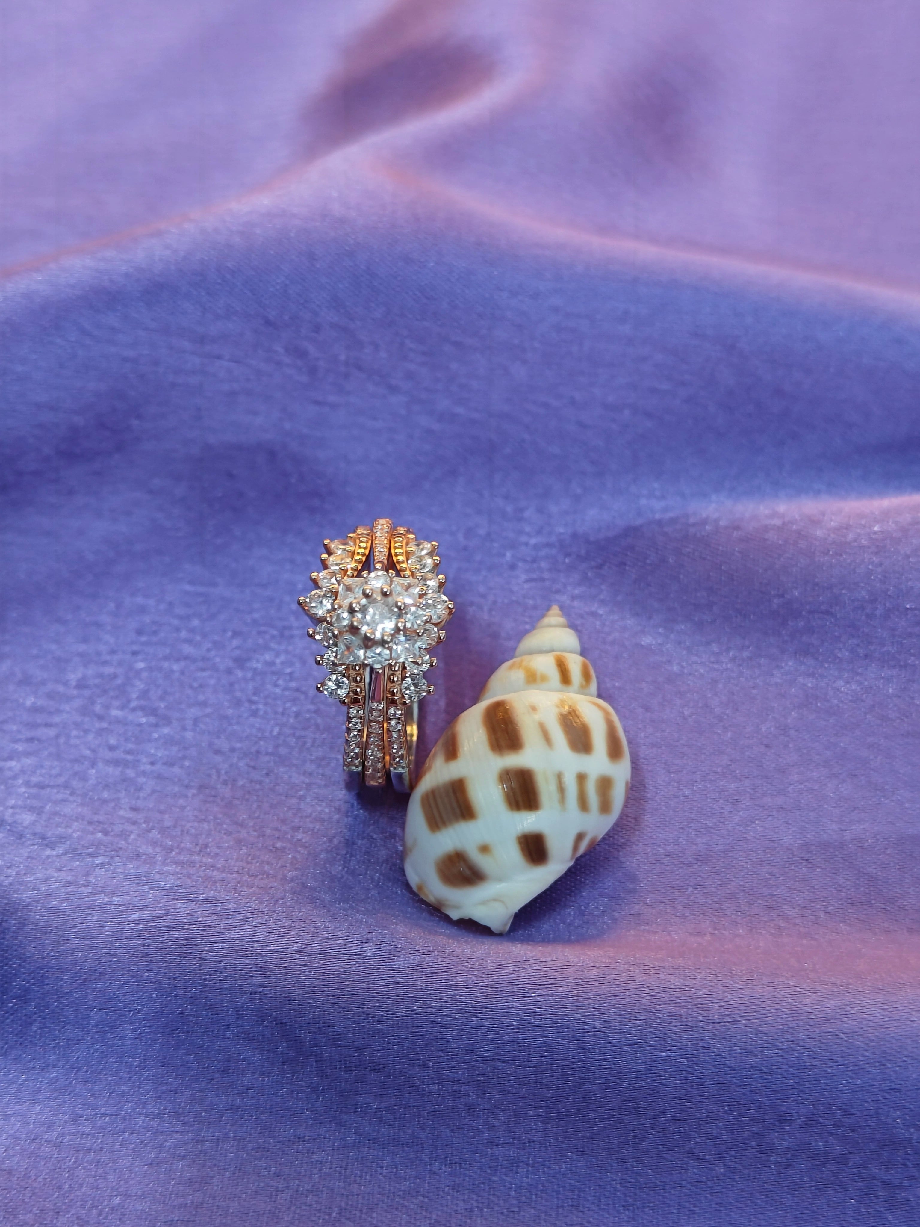 Gold ring with diamonds and a shell on a purple fabric background