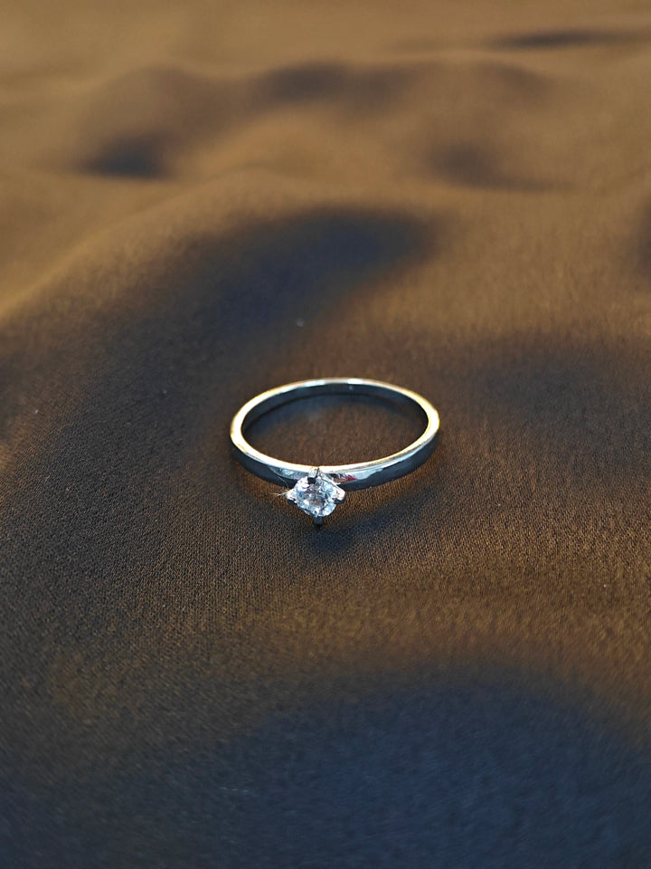 Silver ring with a diamond on sand