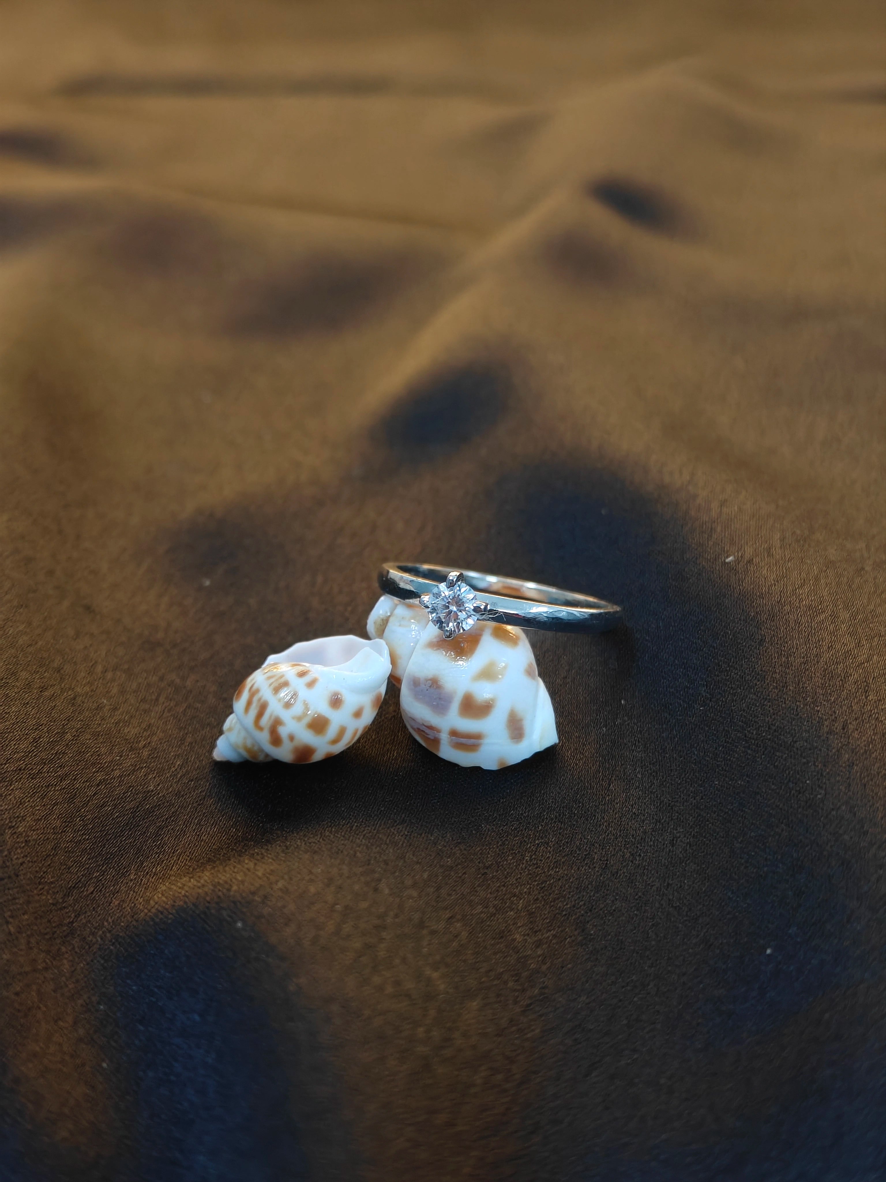 Ring with a diamond on a shell on sand