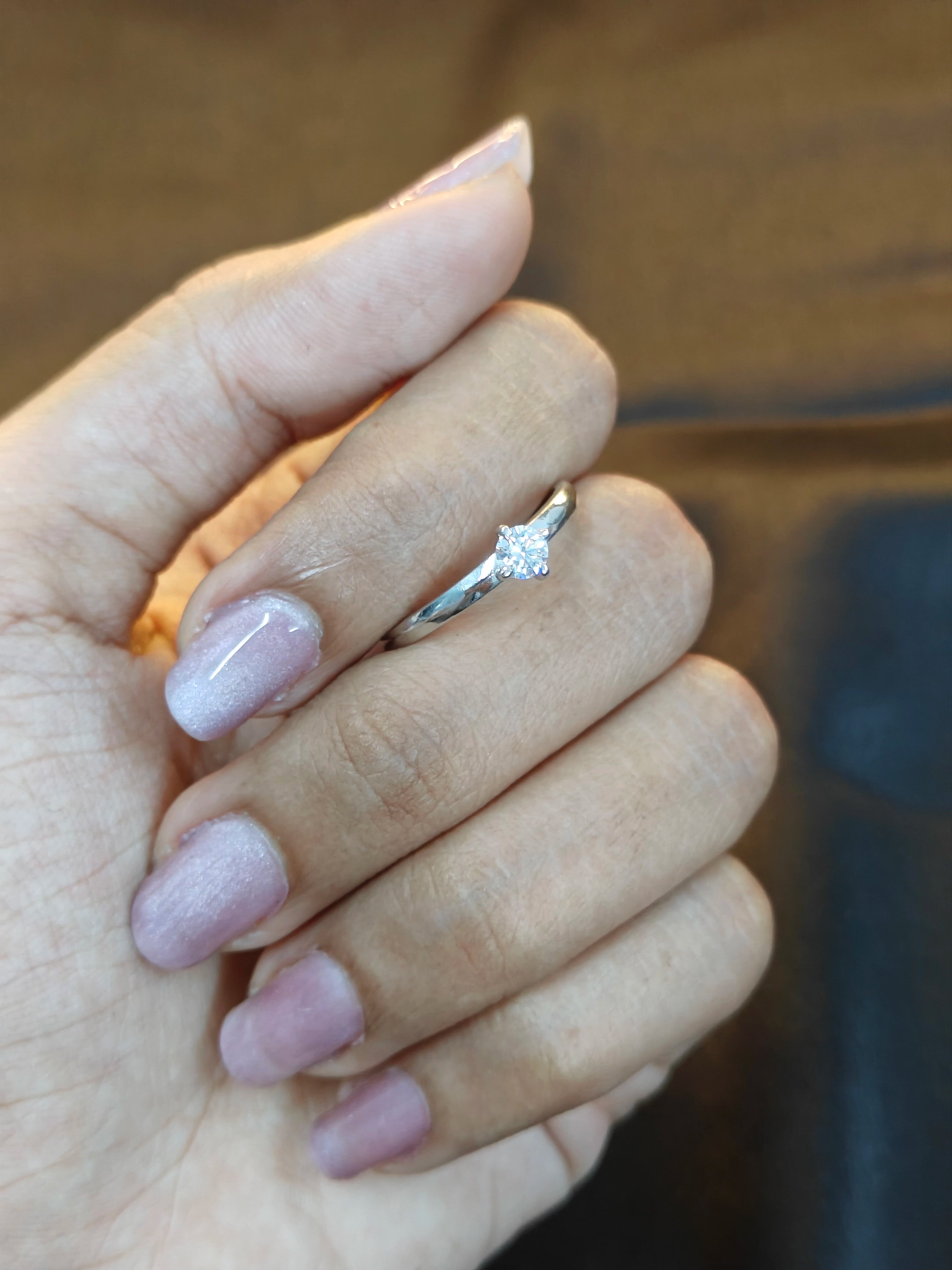Hand with pink nail polish wearing a silver ring on a blurred background