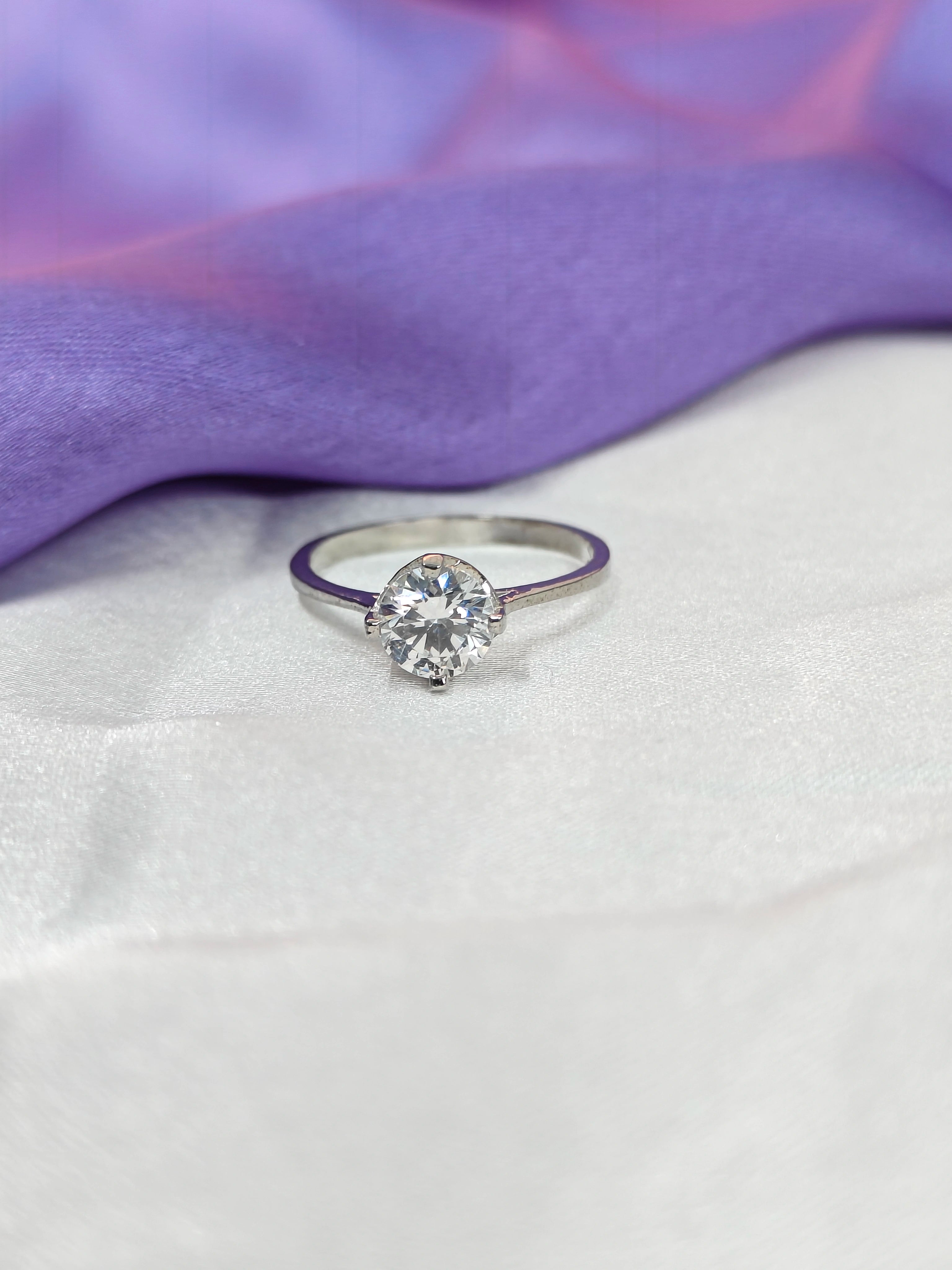 Diamond ring on a white surface with a purple fabric background
