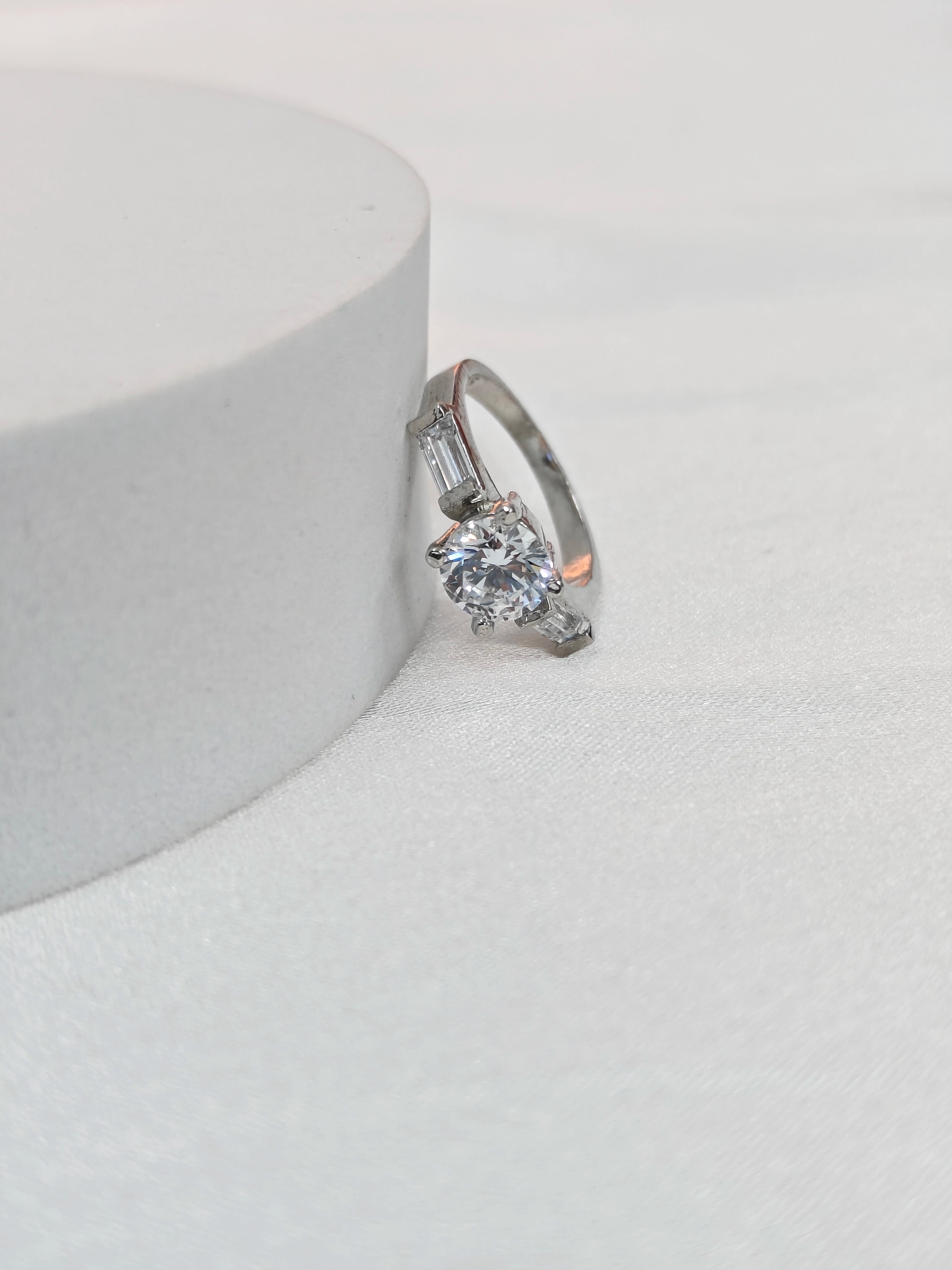 Silver ring with a diamond on a white surface