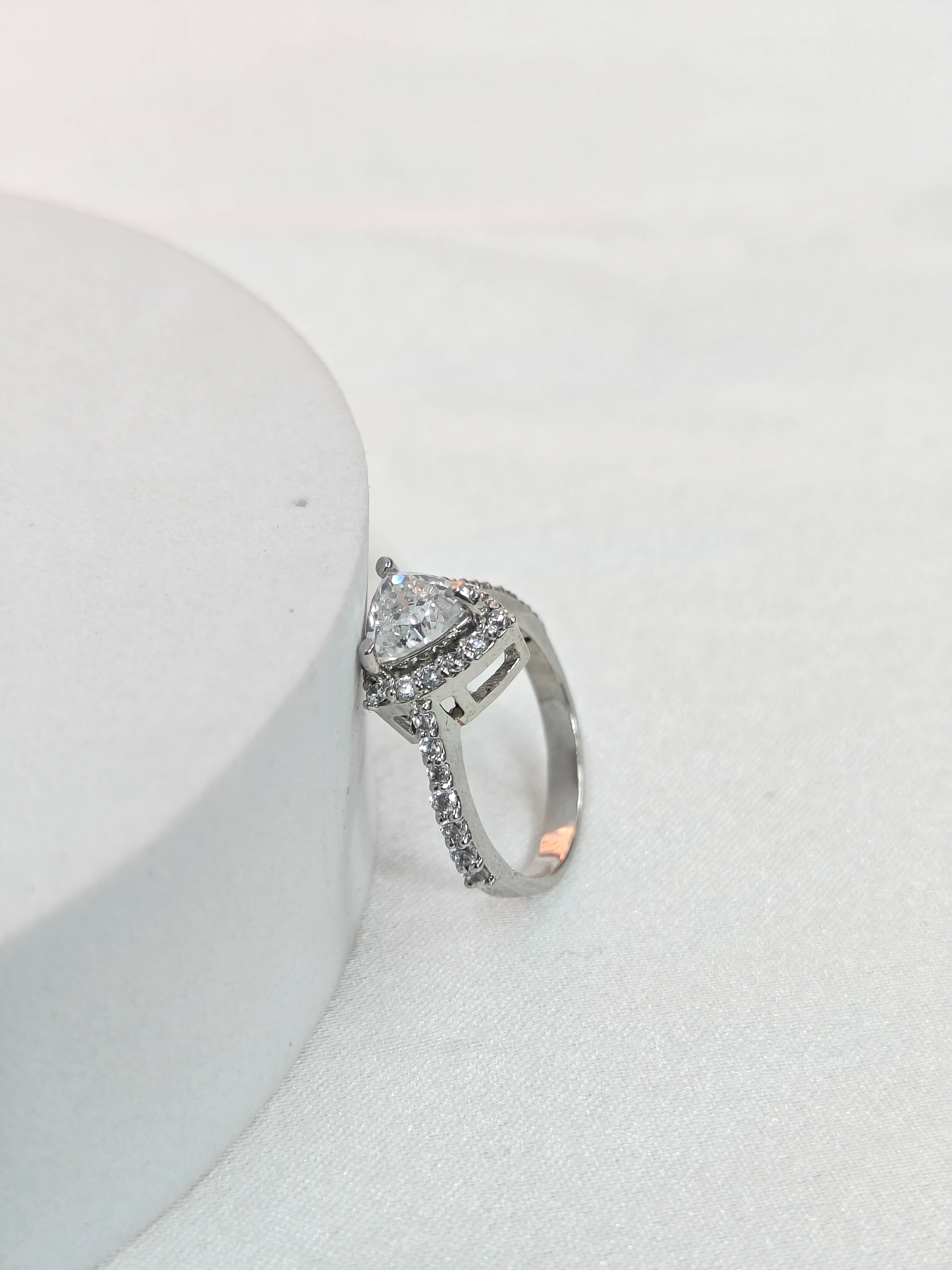 Silver ring with a diamond on a white surface