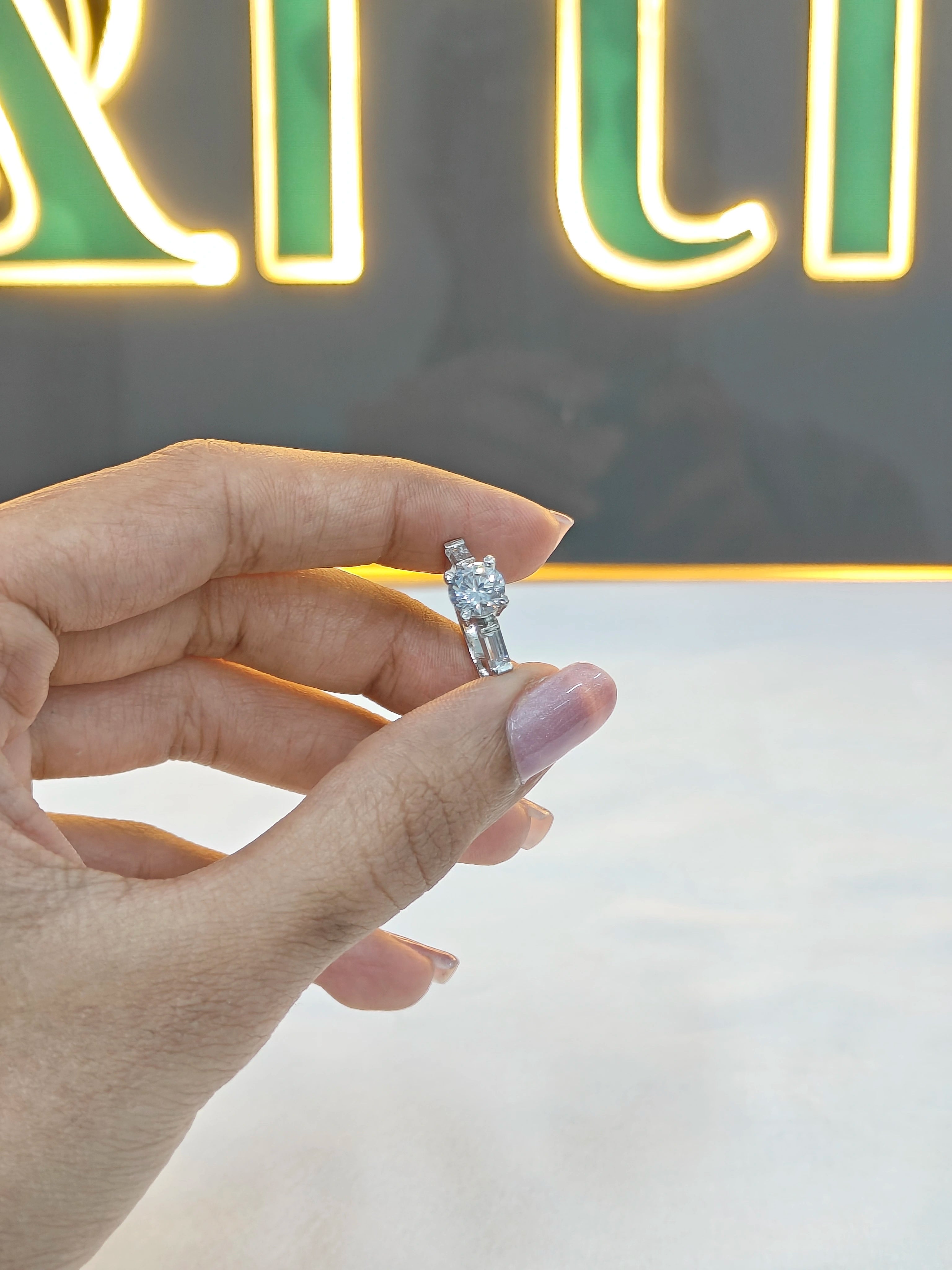 Hand holding a diamond ring with a neon sign in the background