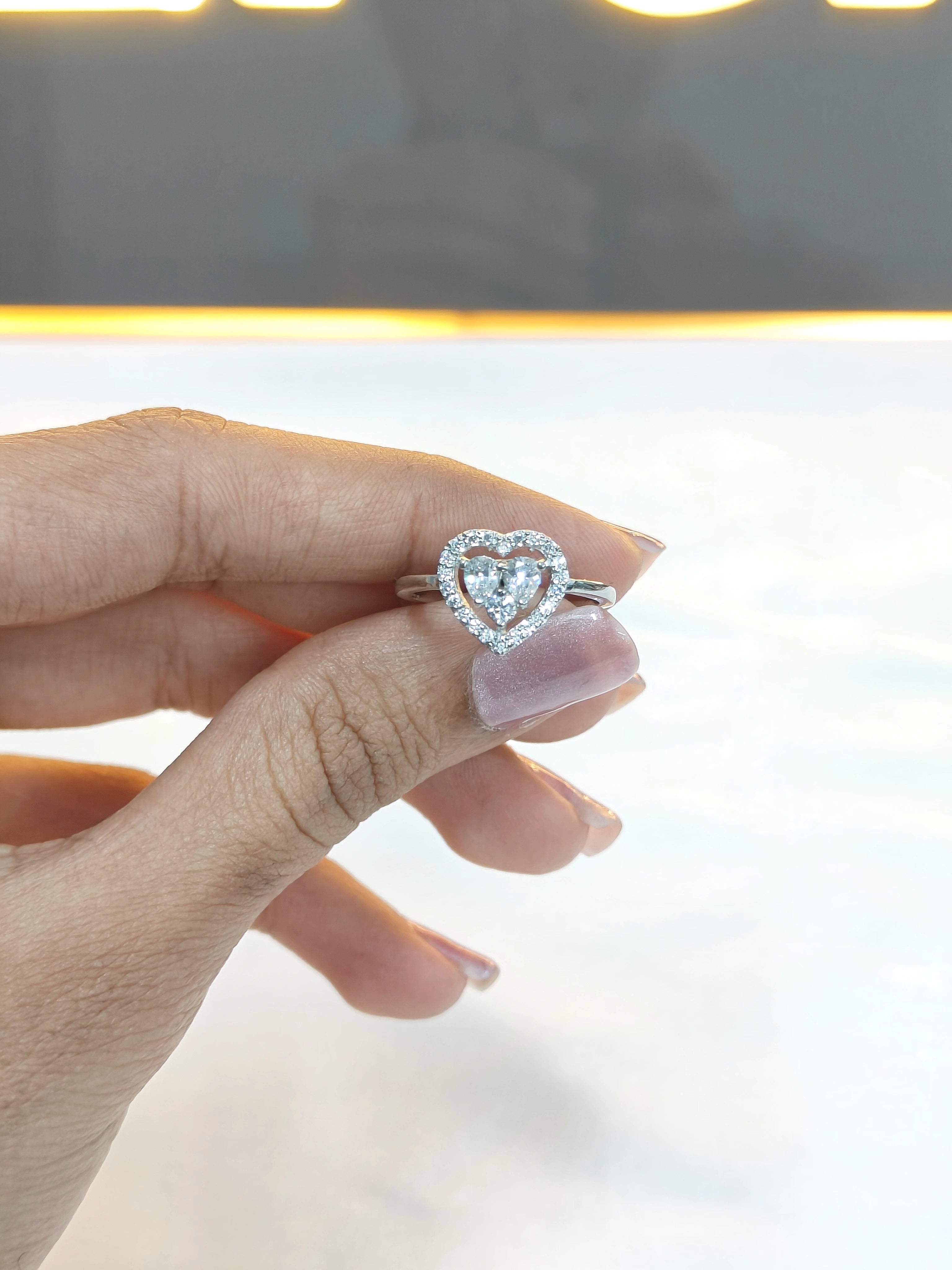 Heart-shaped diamond ring on a hand with a blurred background