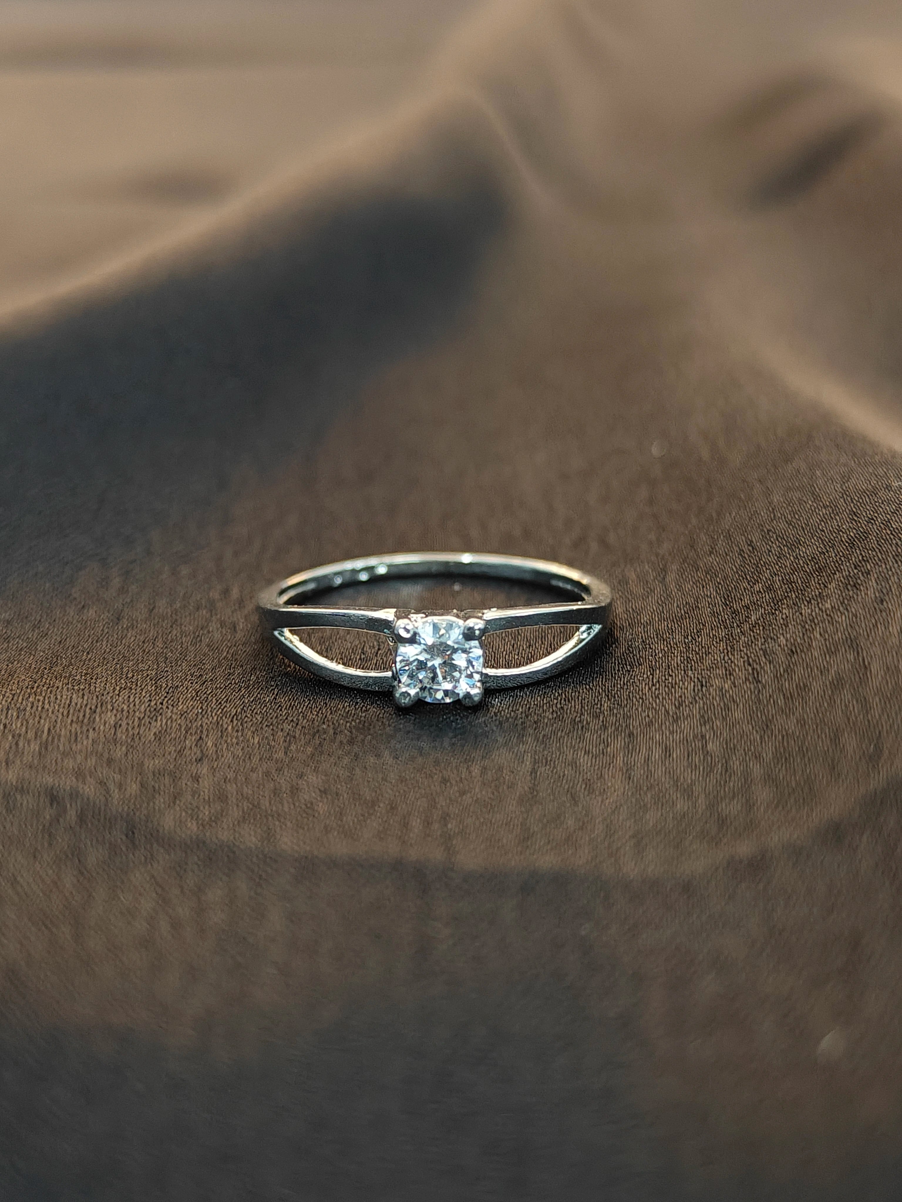 Silver ring with a diamond on a brown fabric background