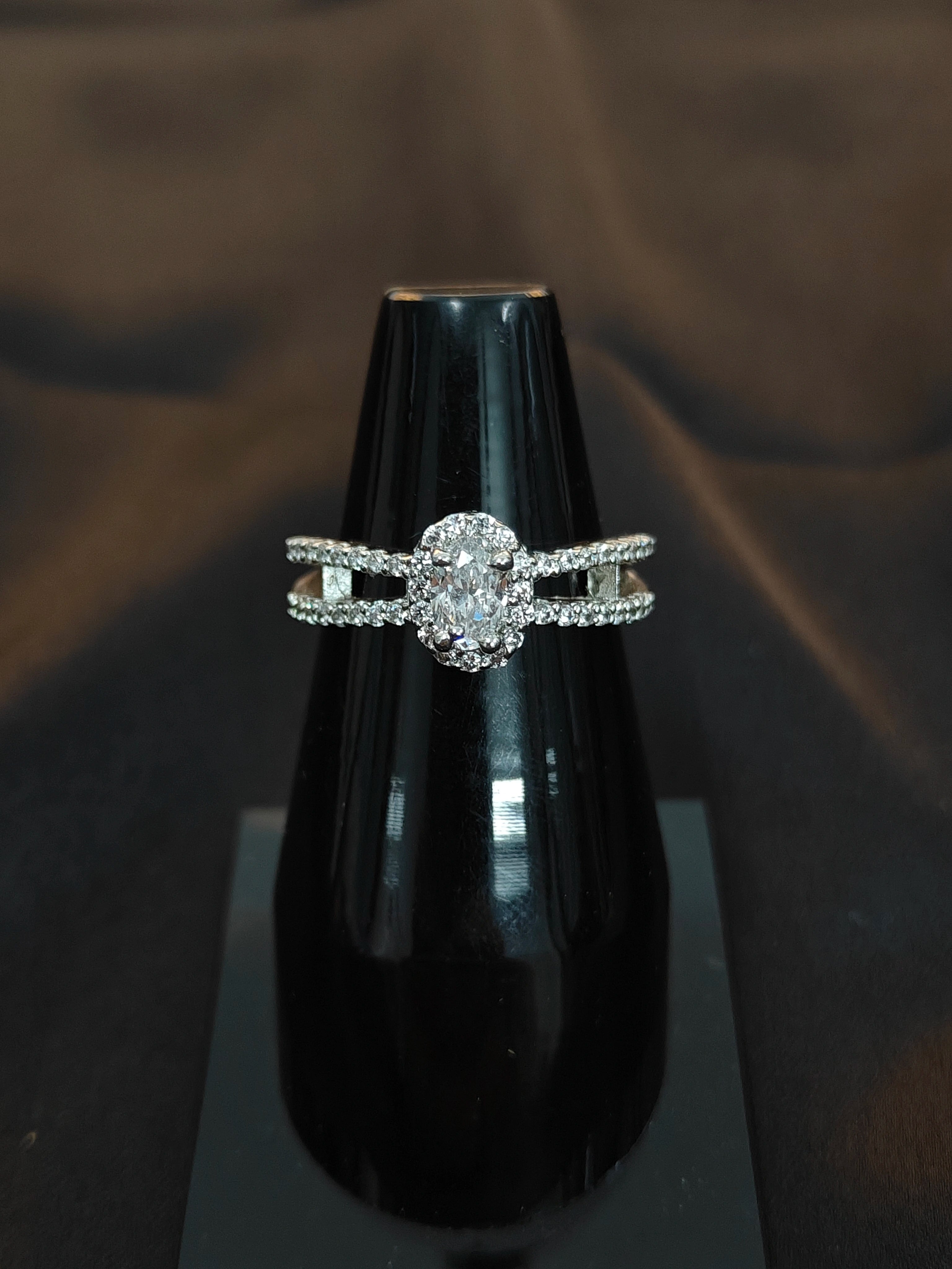 Silver ring with diamonds on a black stand against a dark background