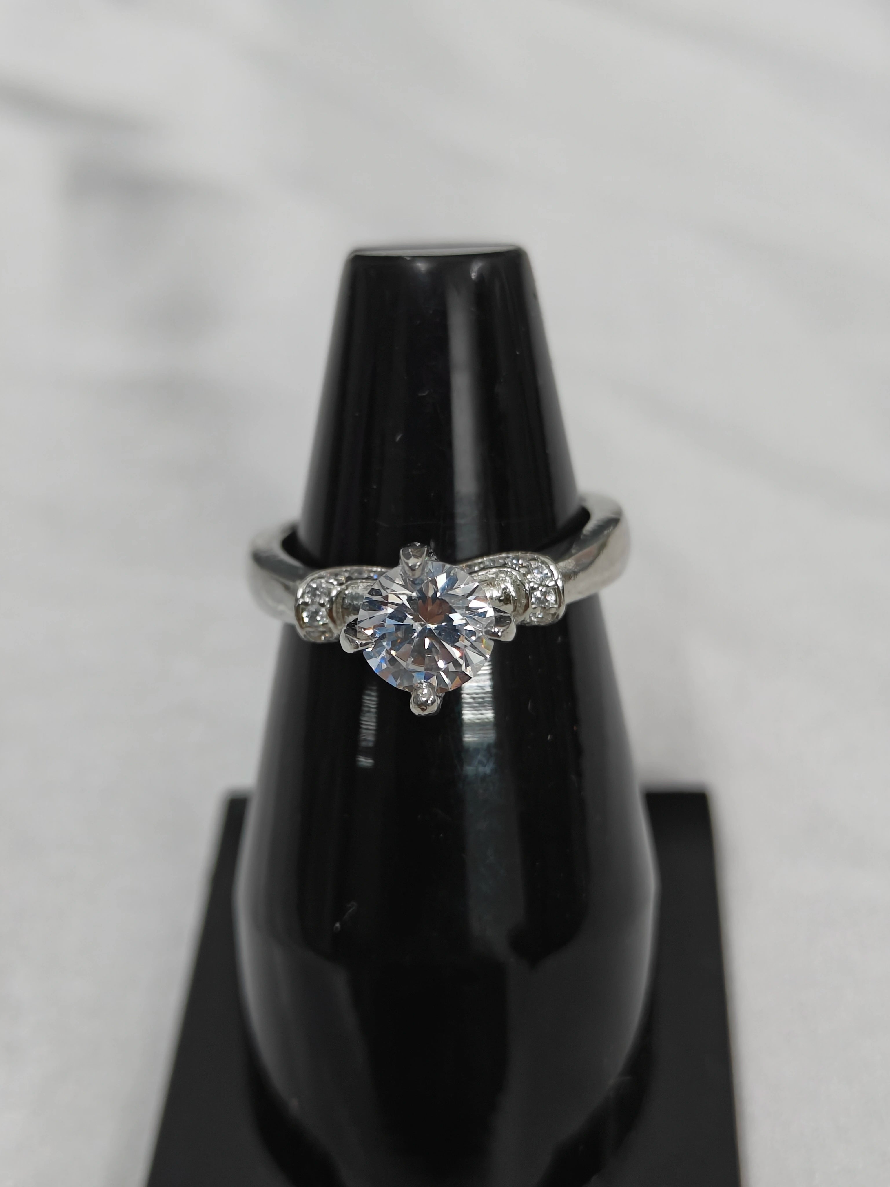 Diamond ring on a black stand with a white background