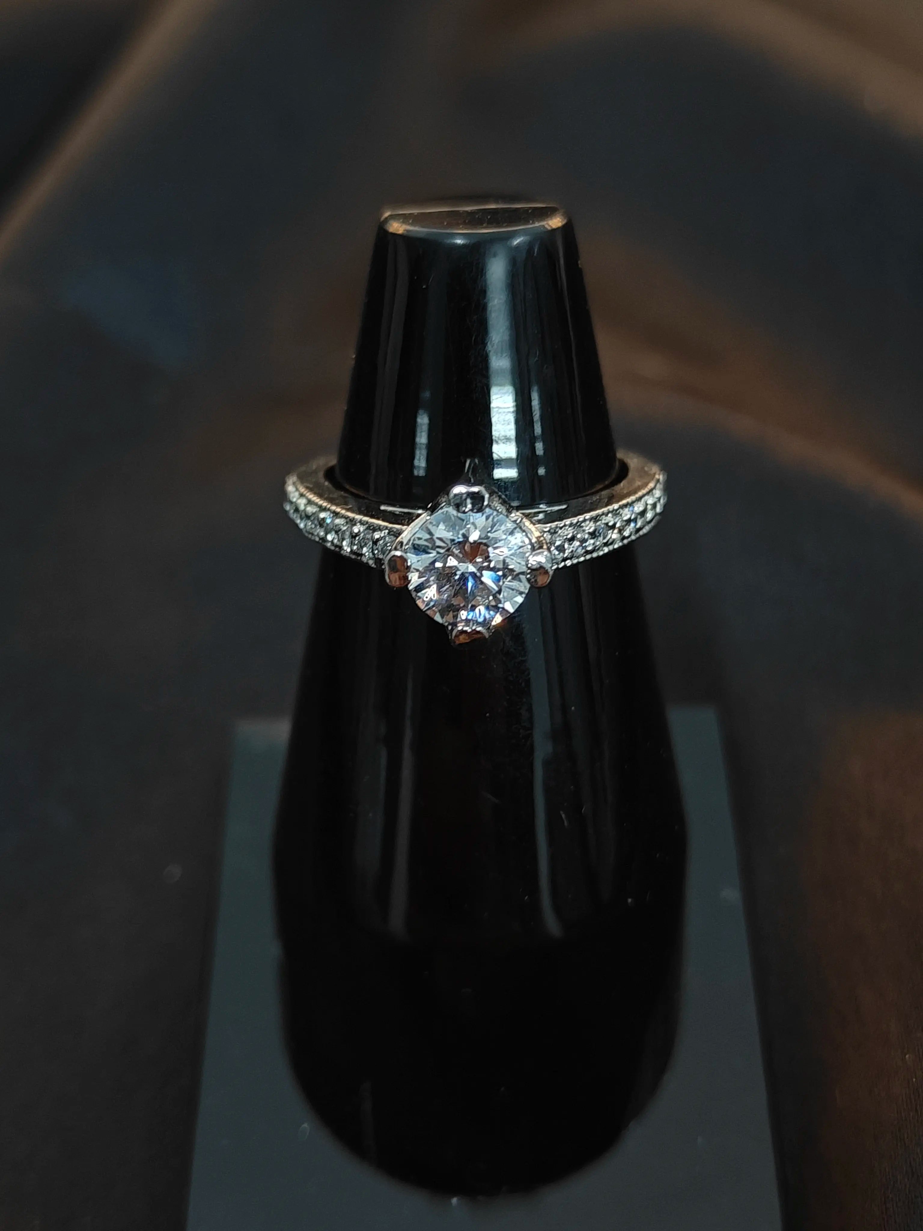 Diamond ring on a black stand against a dark background