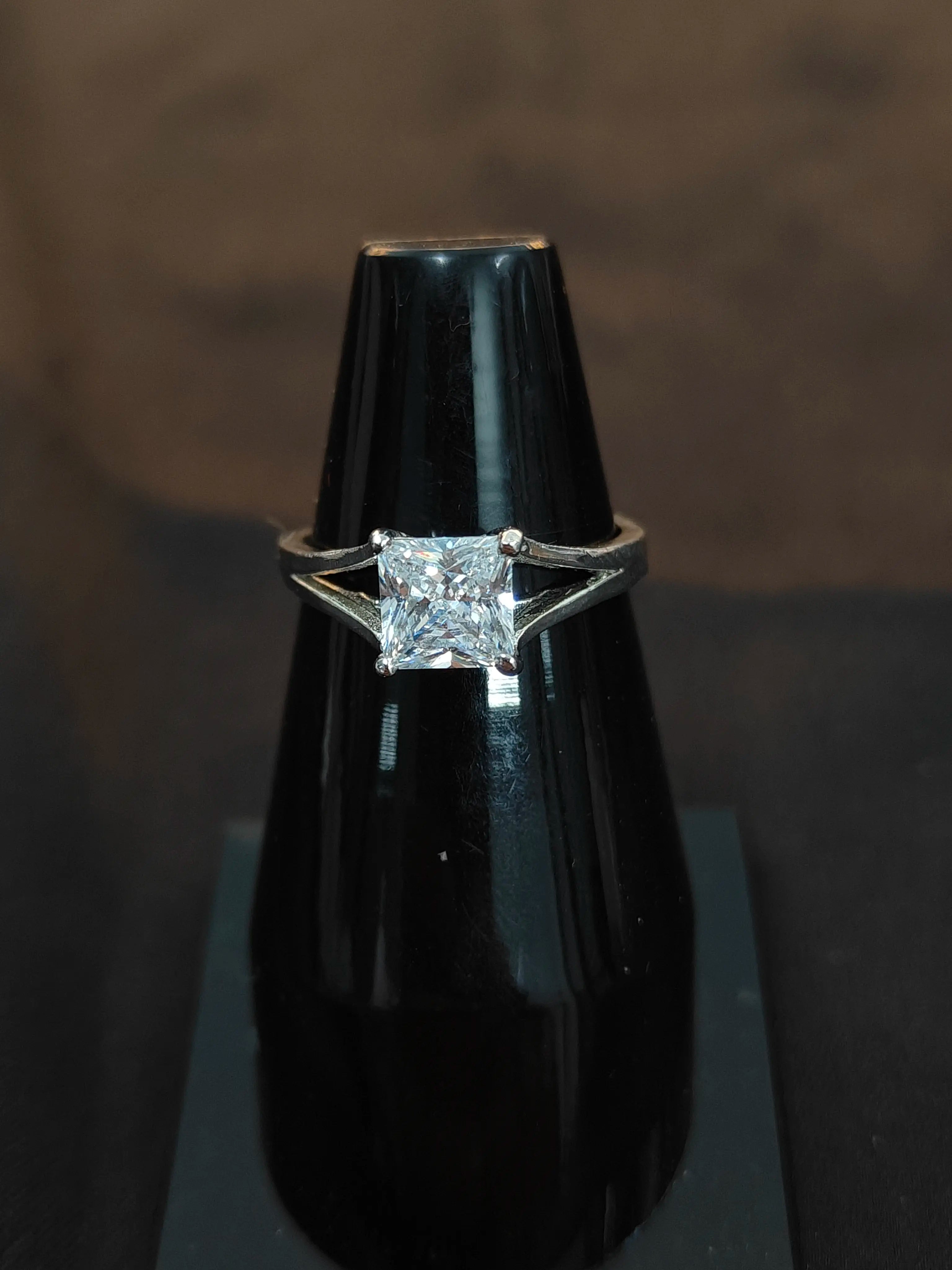 Diamond ring on a black stand against a dark background