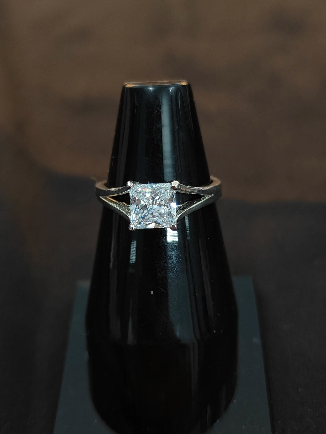 Diamond ring on a black stand against a dark background