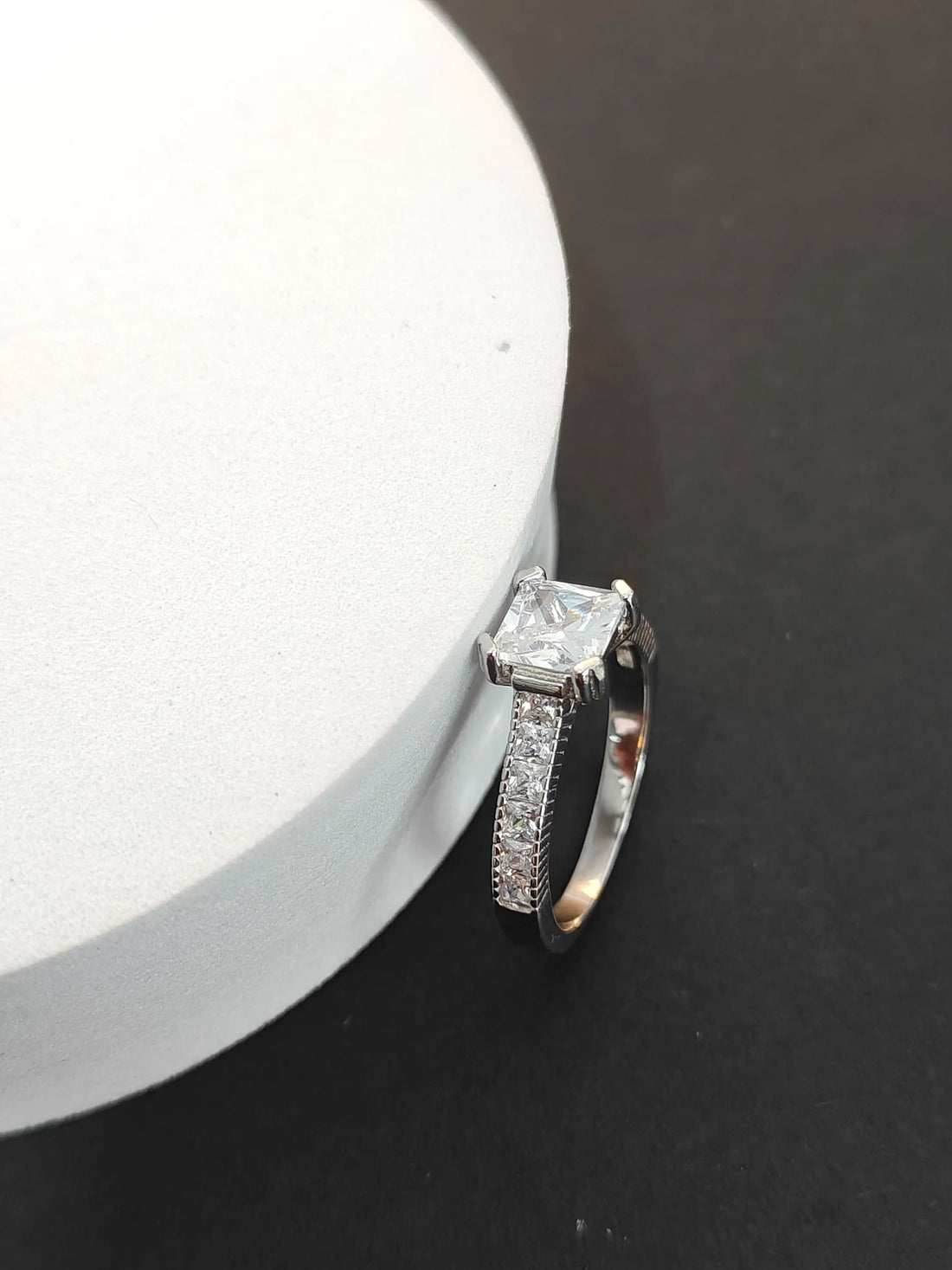 Diamond ring on a dark surface with a white circular object