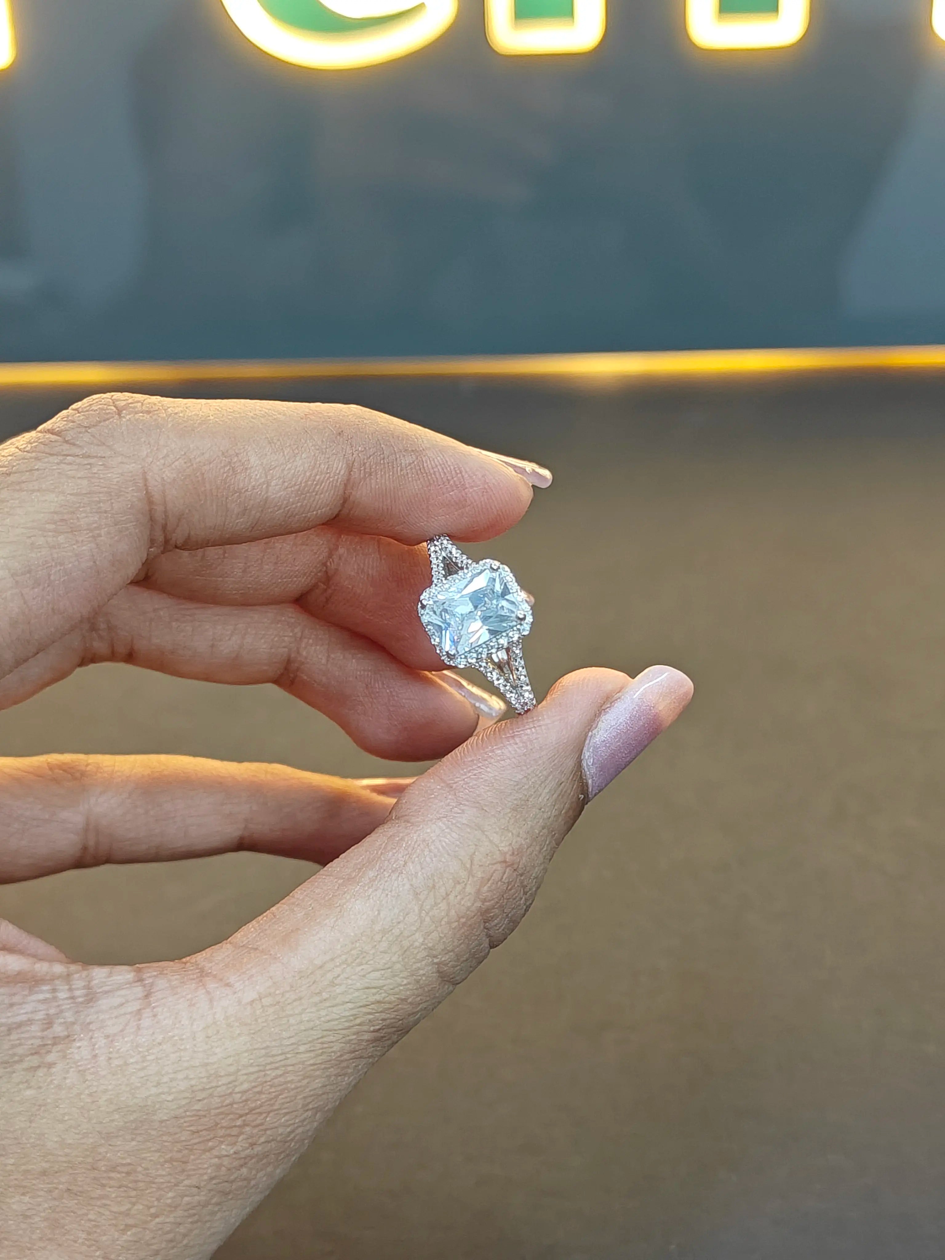 Hand holding a diamond ring with a blurred background