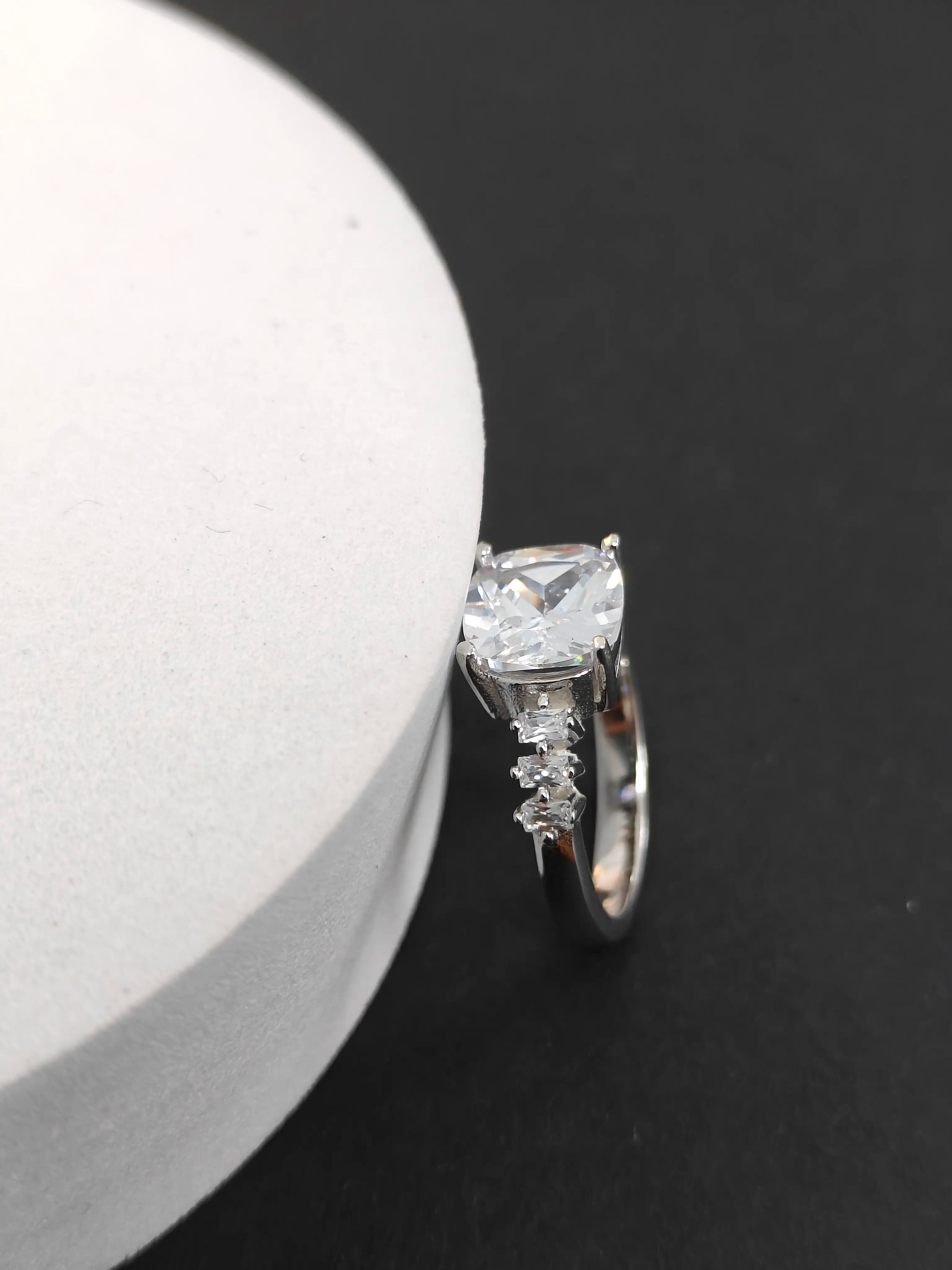 Silver ring with a large diamond and smaller stones on a black background