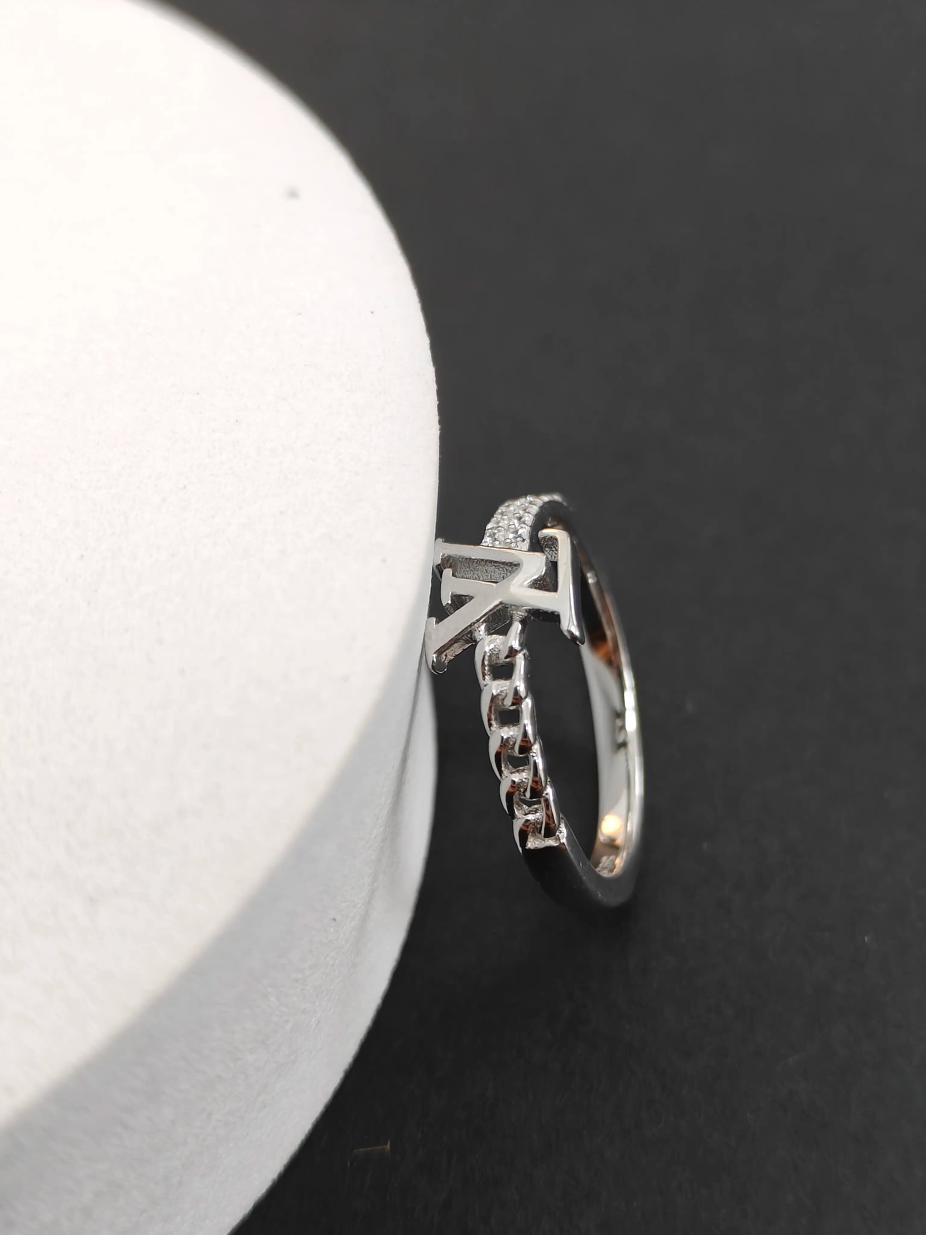Silver ring with chain detail on a black and white background