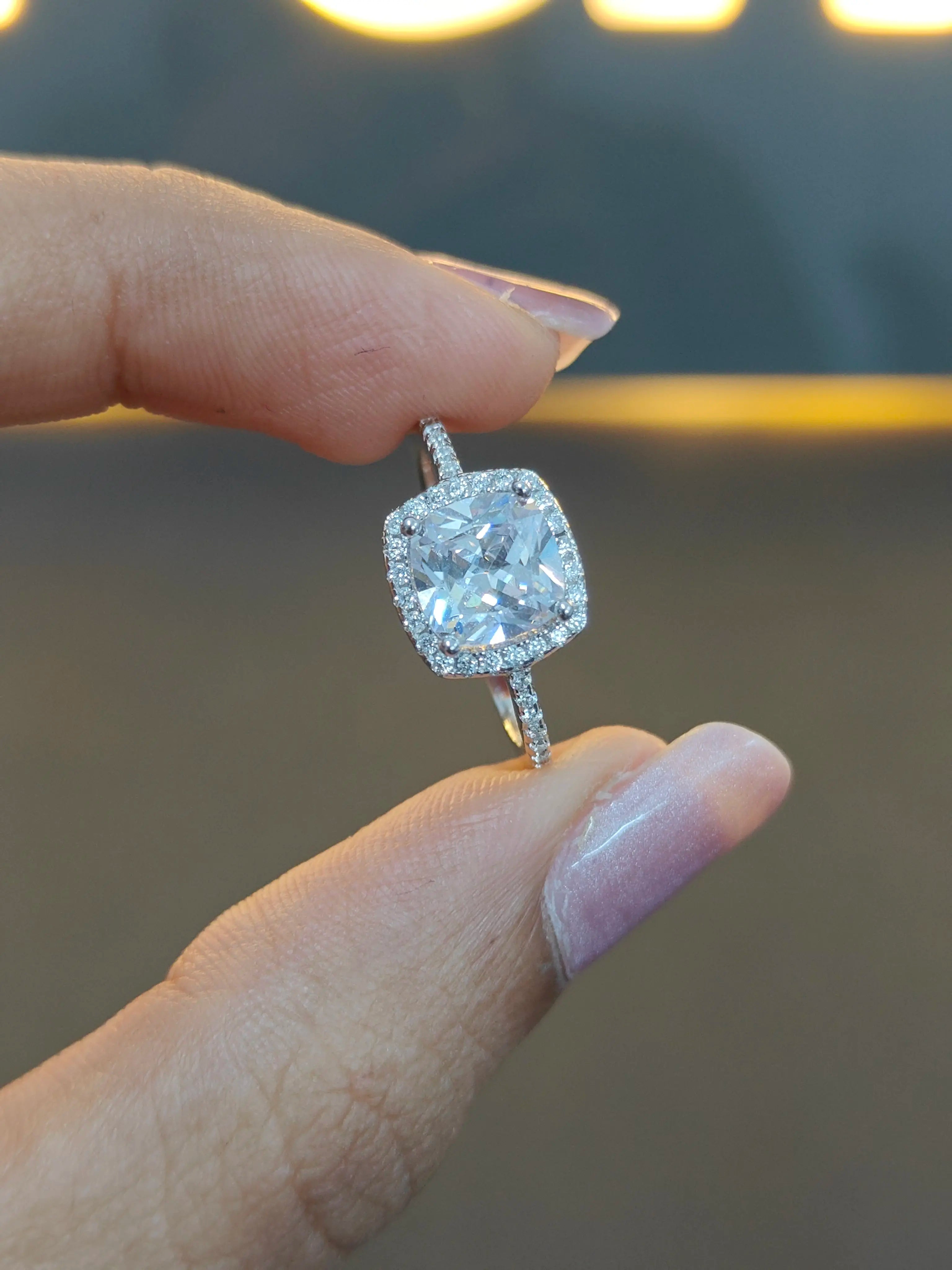 Diamond ring held between fingers with a blurred background