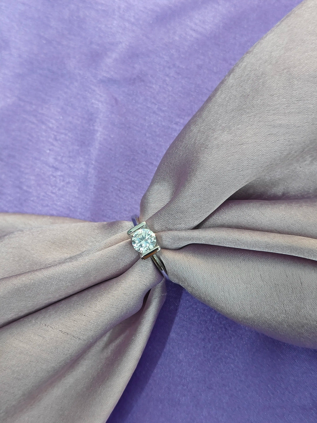 Diamond ring on a knotted gray fabric with a purple background