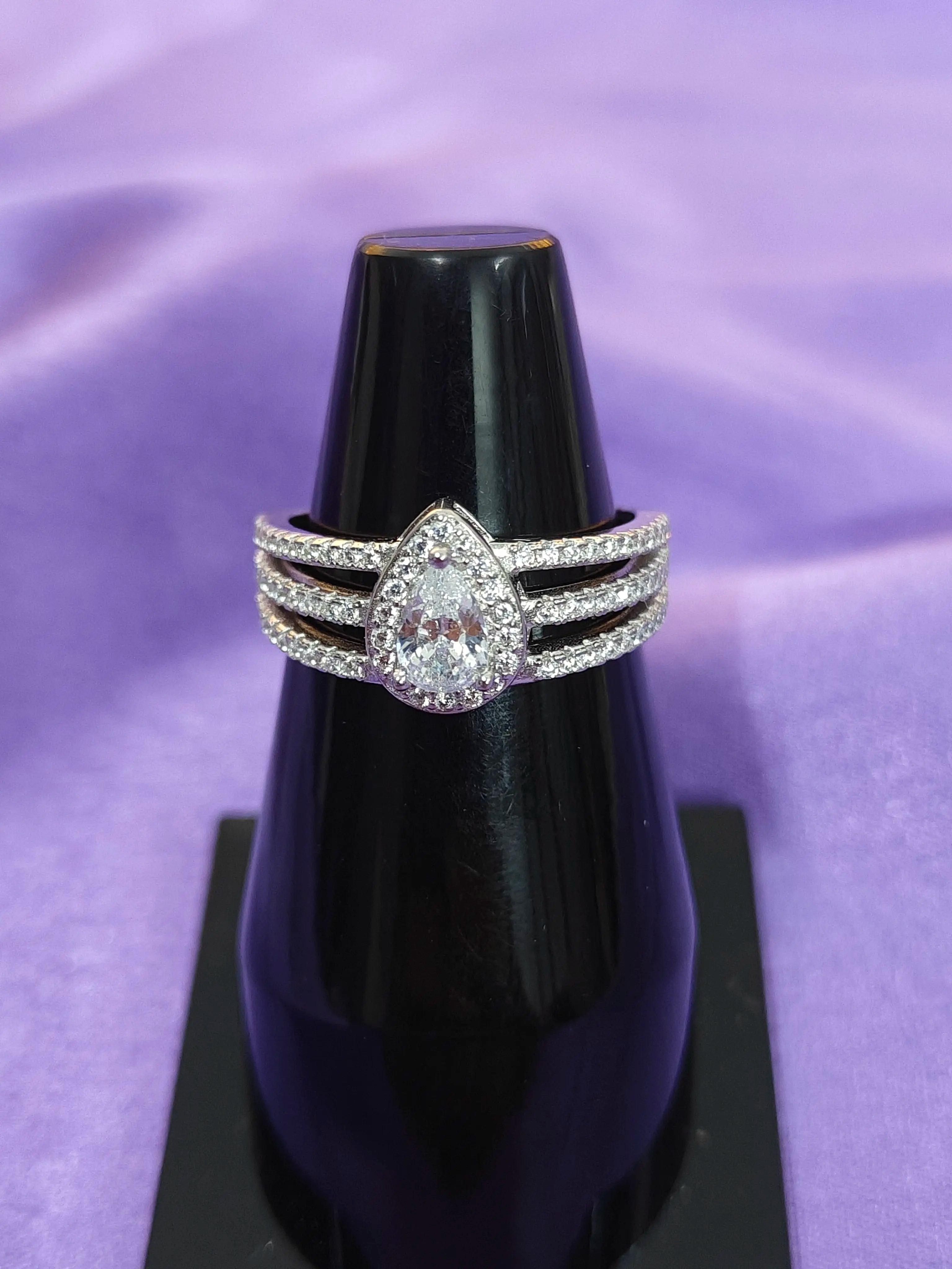 Two diamond rings on a black stand against a purple background