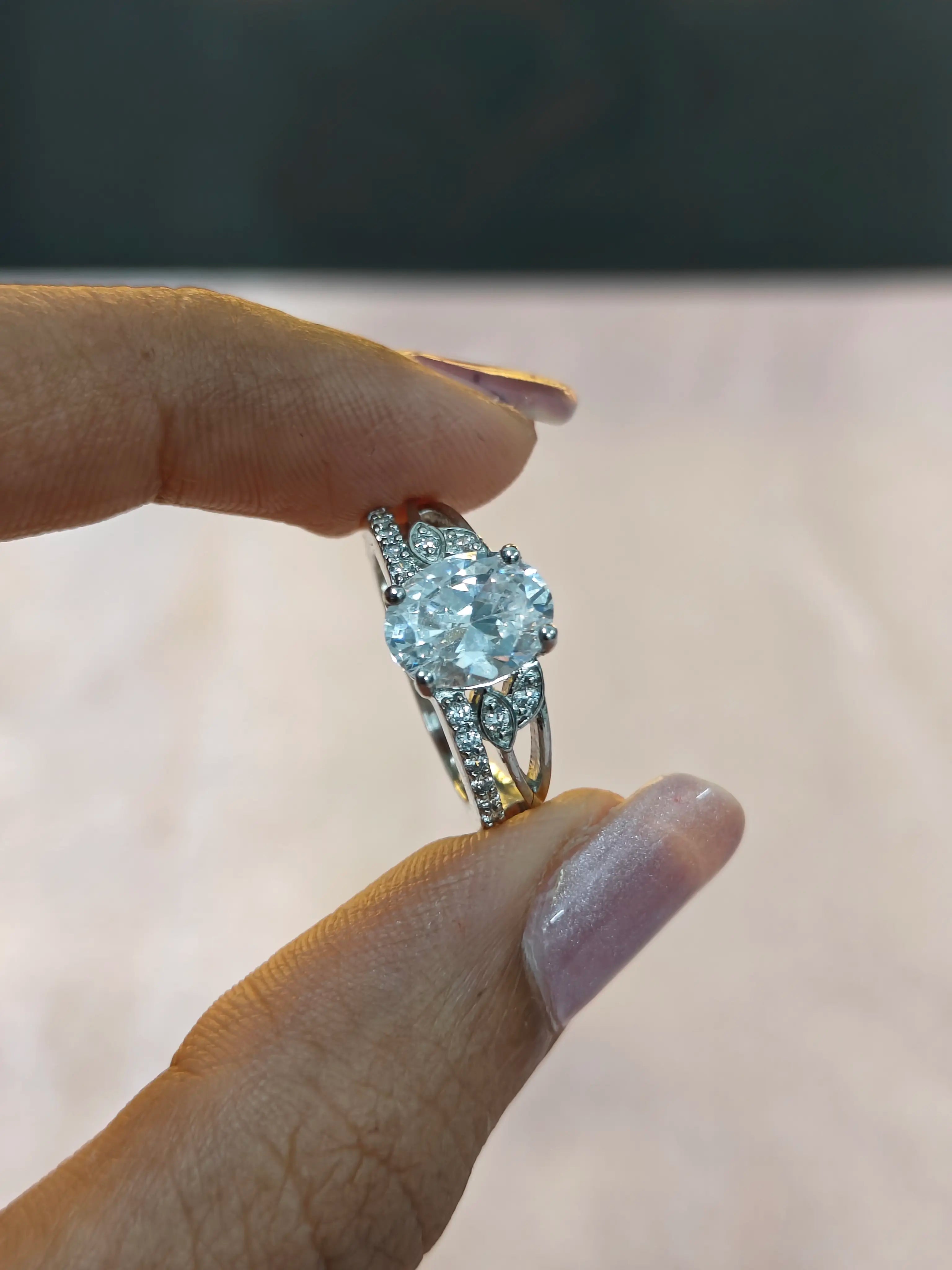 Diamond ring held between fingers against a neutral background